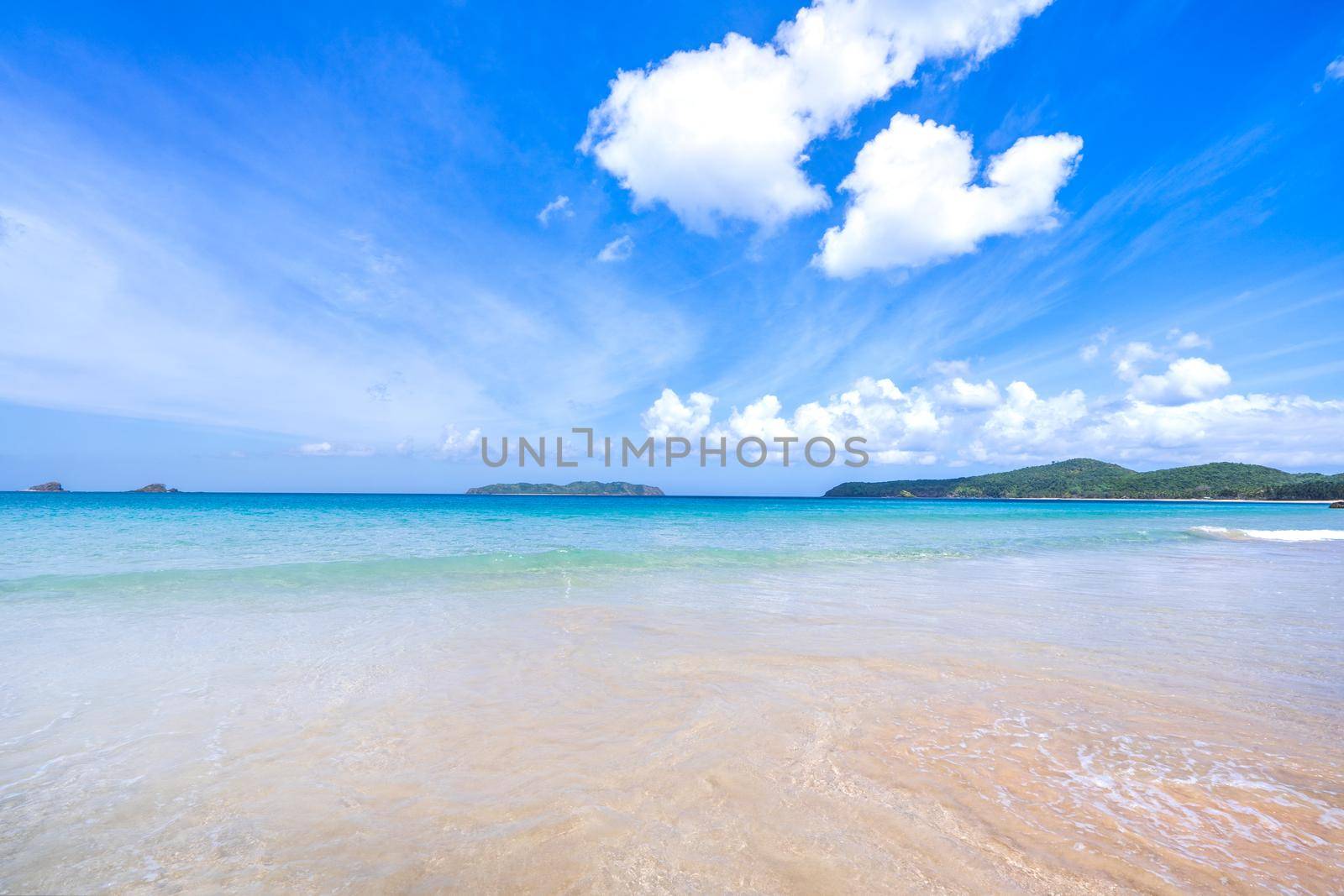 Beautiful amazing gold colored sandy beach with soft waves isolated with sunny blue sky. Concept of tropical calm tourism idea, copy space, close up