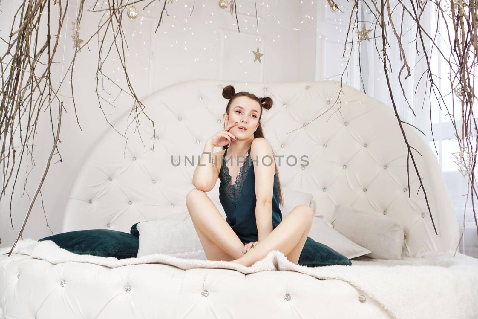 Sexy beautiful woman sitting on big white bed, relaxing. Girl with long healthy hair