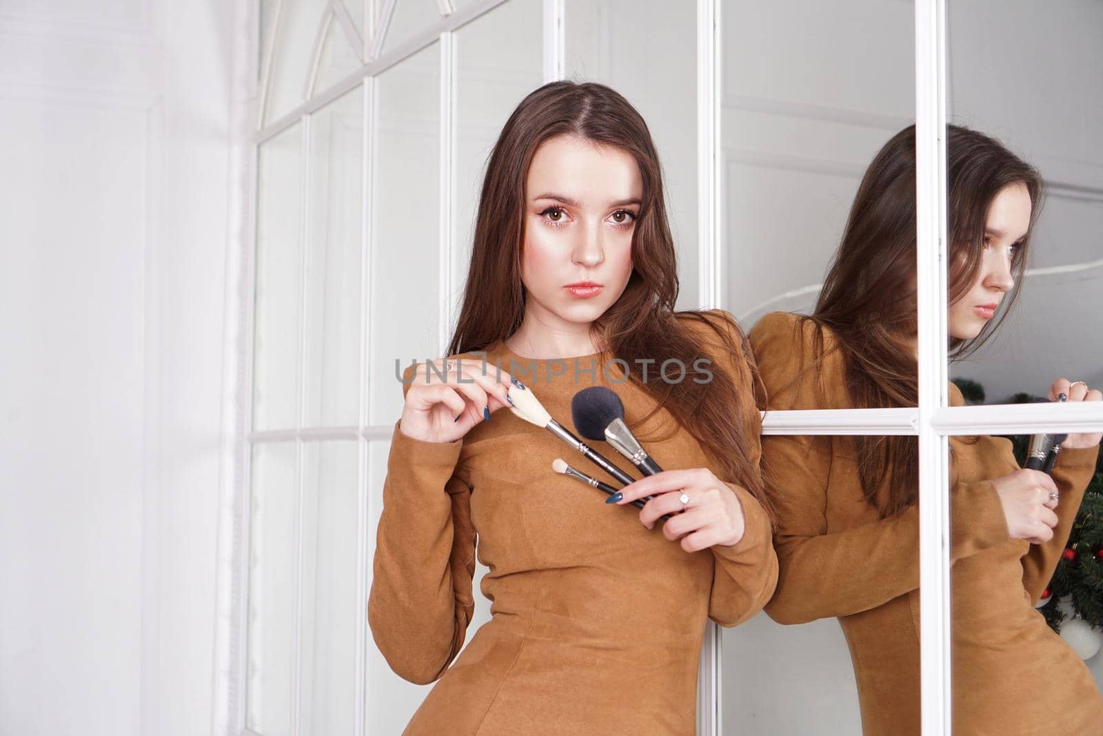 Makeup artist with long dark hair holding a powder brush, haughty expression, reflection in the mirror