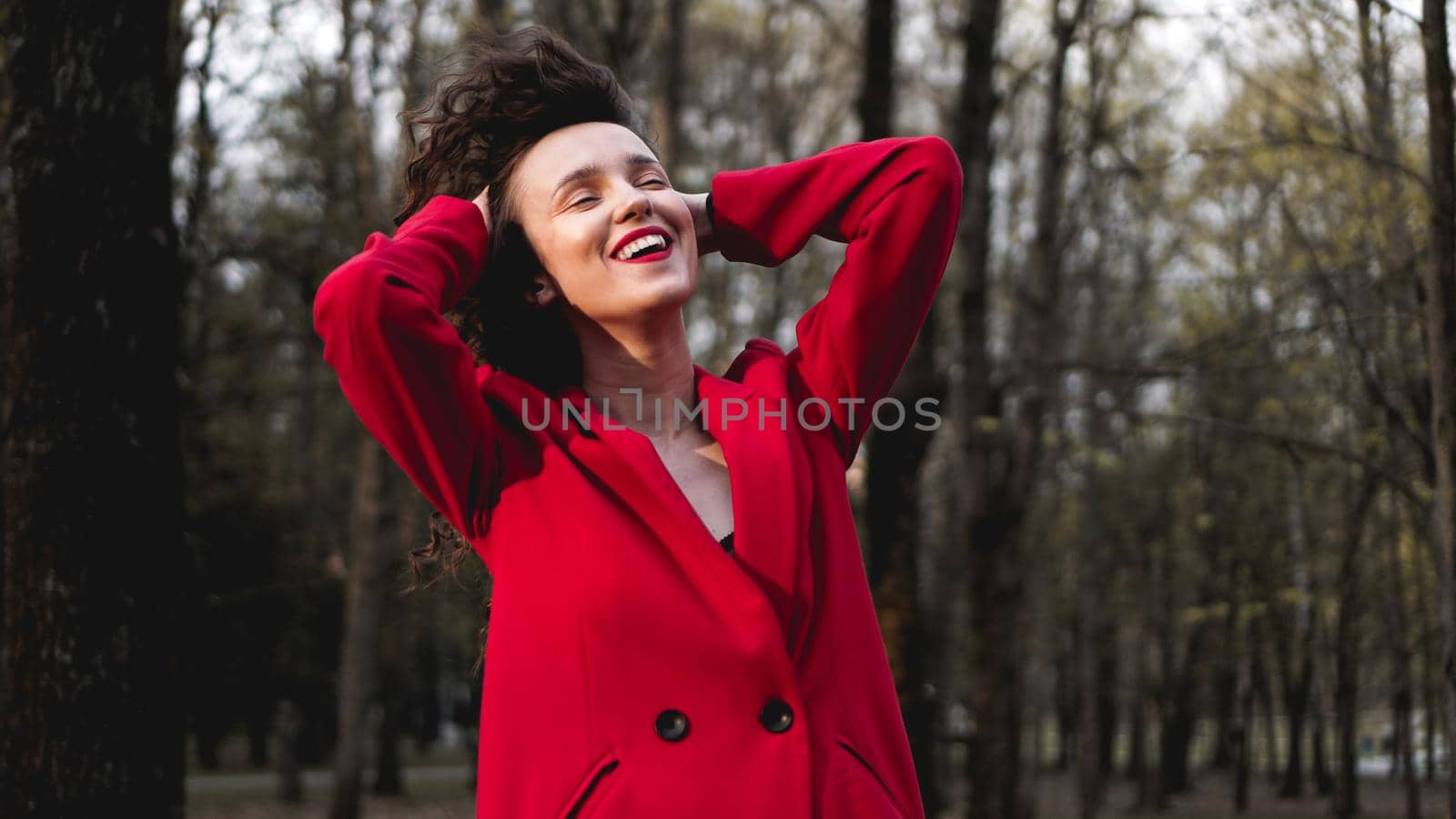 Glamorous woman wearing red outfit and matching red lip gloss. Portrait in the park