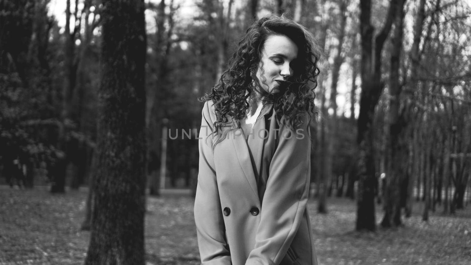 Pretty and happy long hair girl in jacket walking in the forest or park - black and white