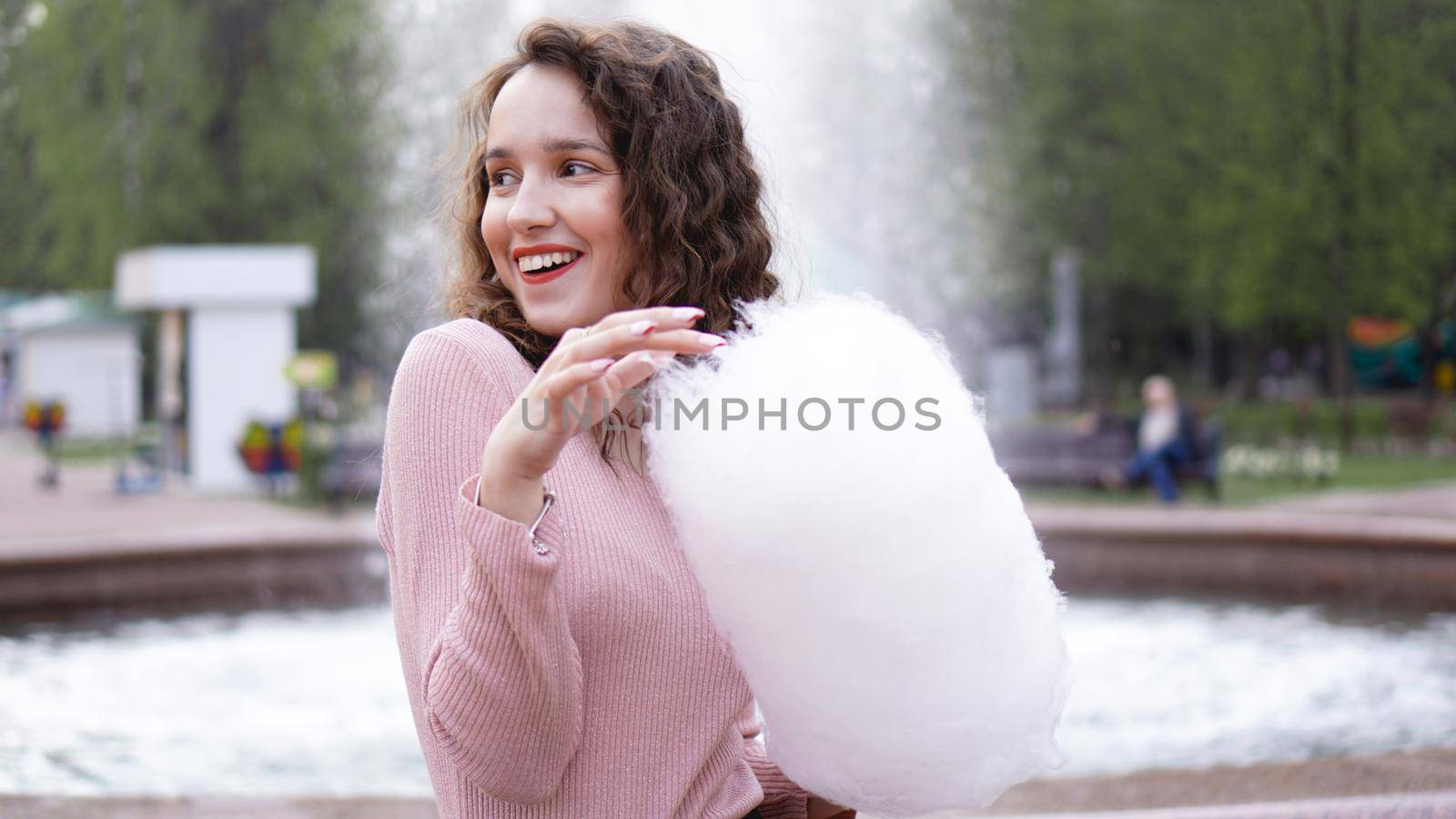 Portrait of a smiling excited girl holding cotton candy at amusement park by natali_brill