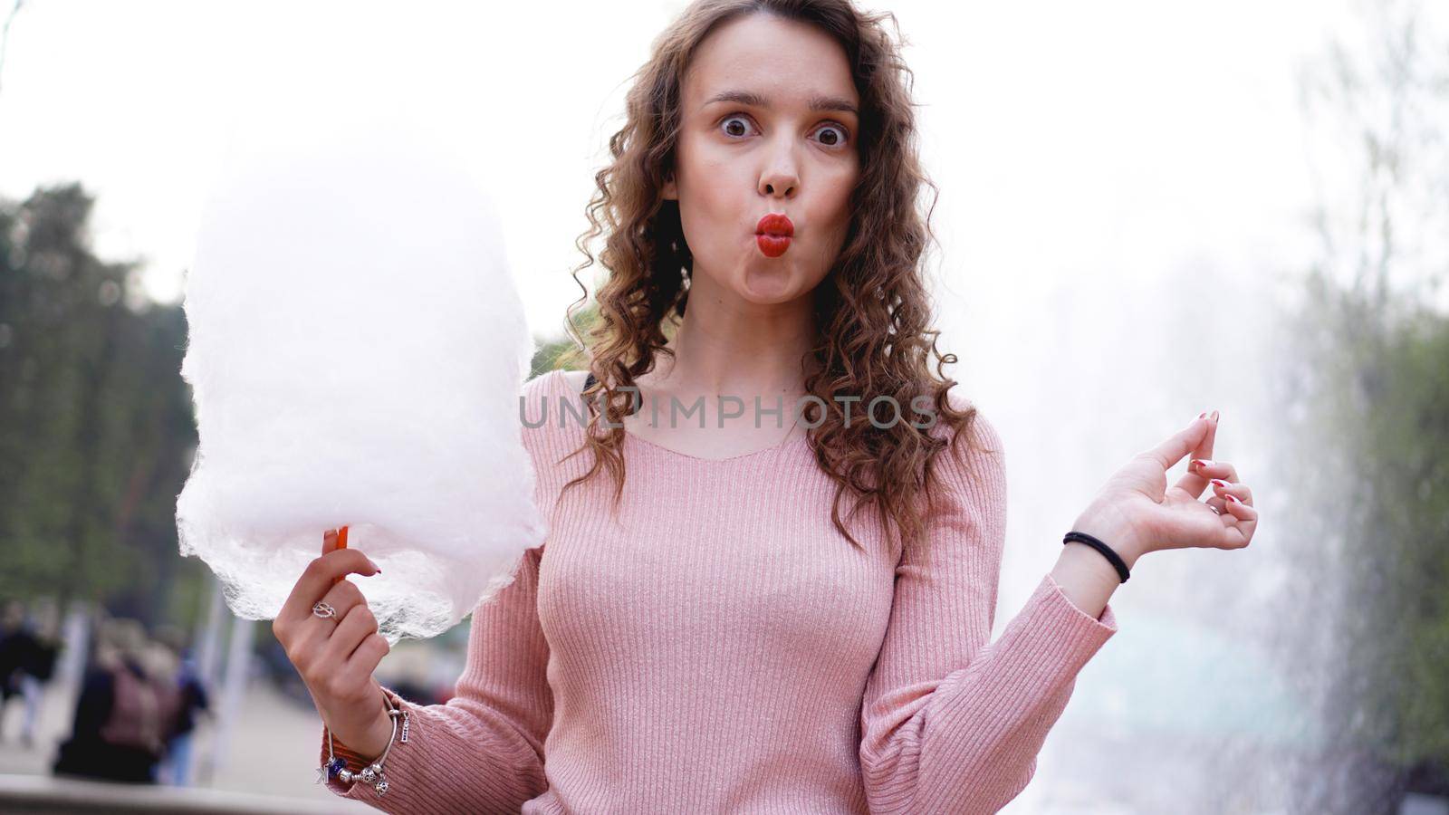 Portrait of a smiling excited girl holding cotton candy at amusement park by natali_brill