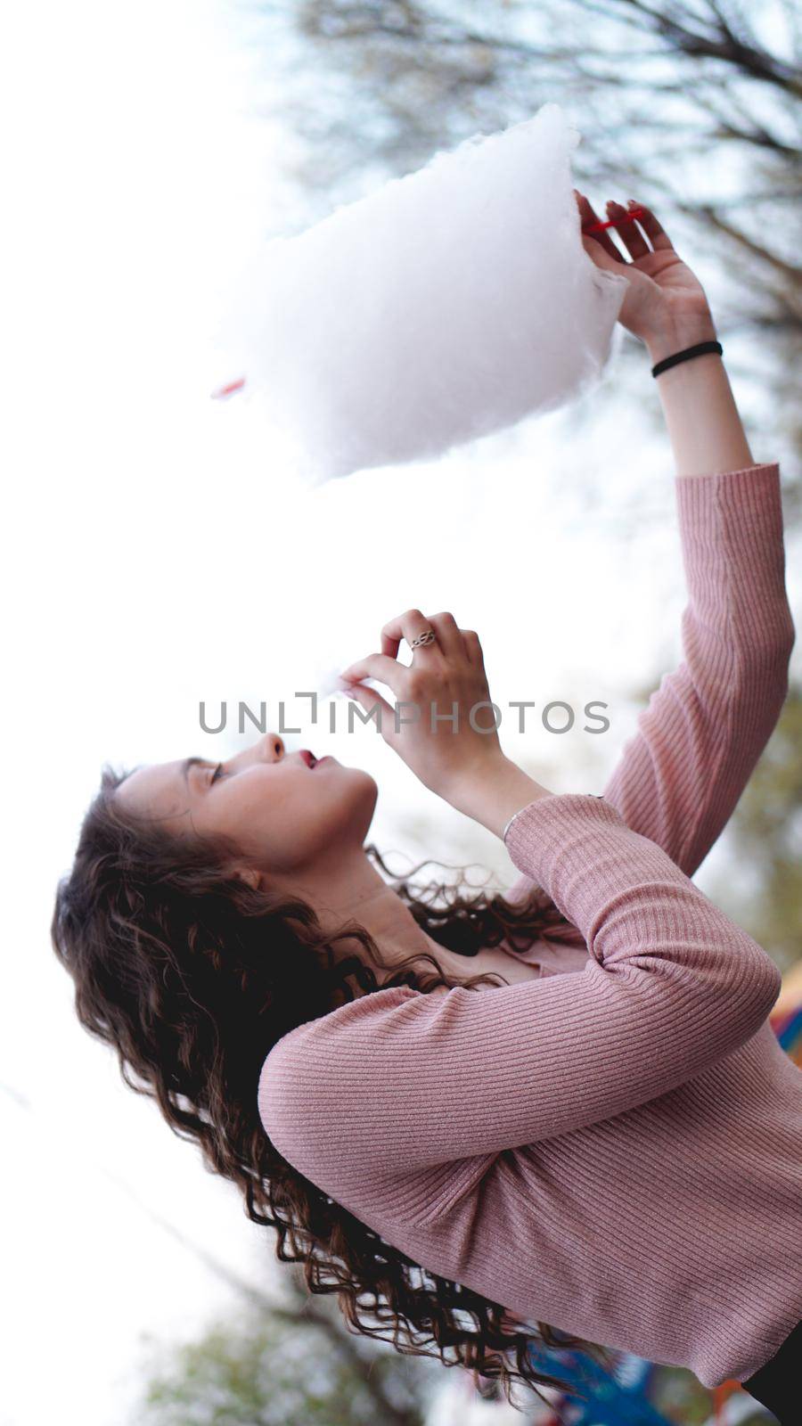 Close up portrait of a happy smiling excited girl holding cotton candy at amusement park