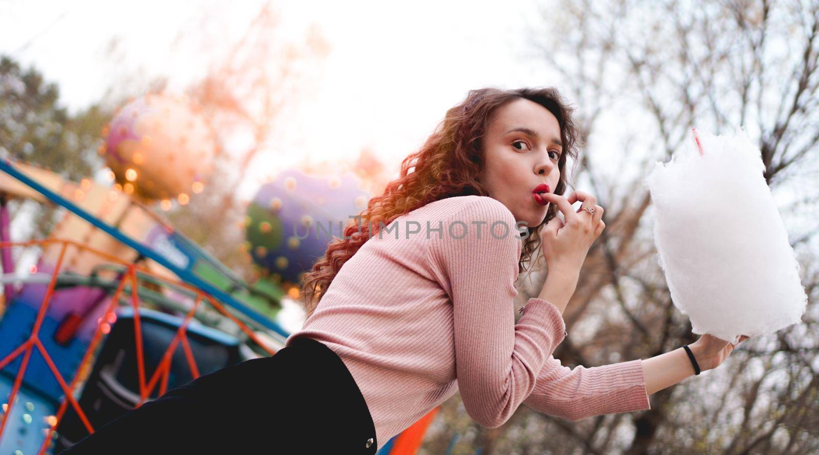 Close up portrait of a happy smiling excited girl holding cotton candy at amusement park