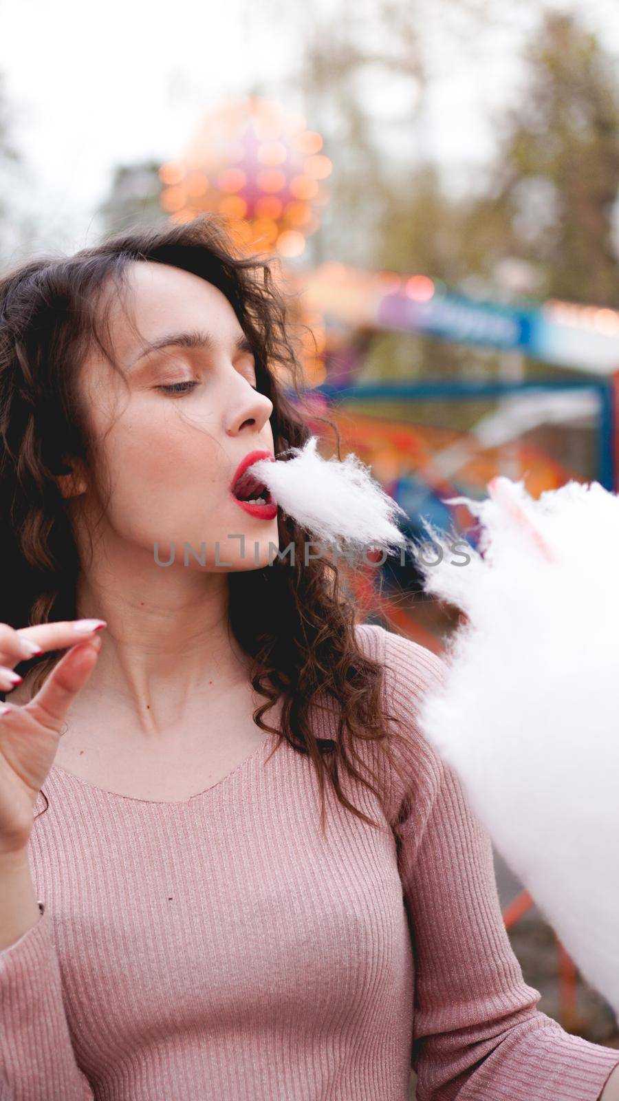 Portrait of a smiling excited girl holding cotton candy at amusement park by natali_brill