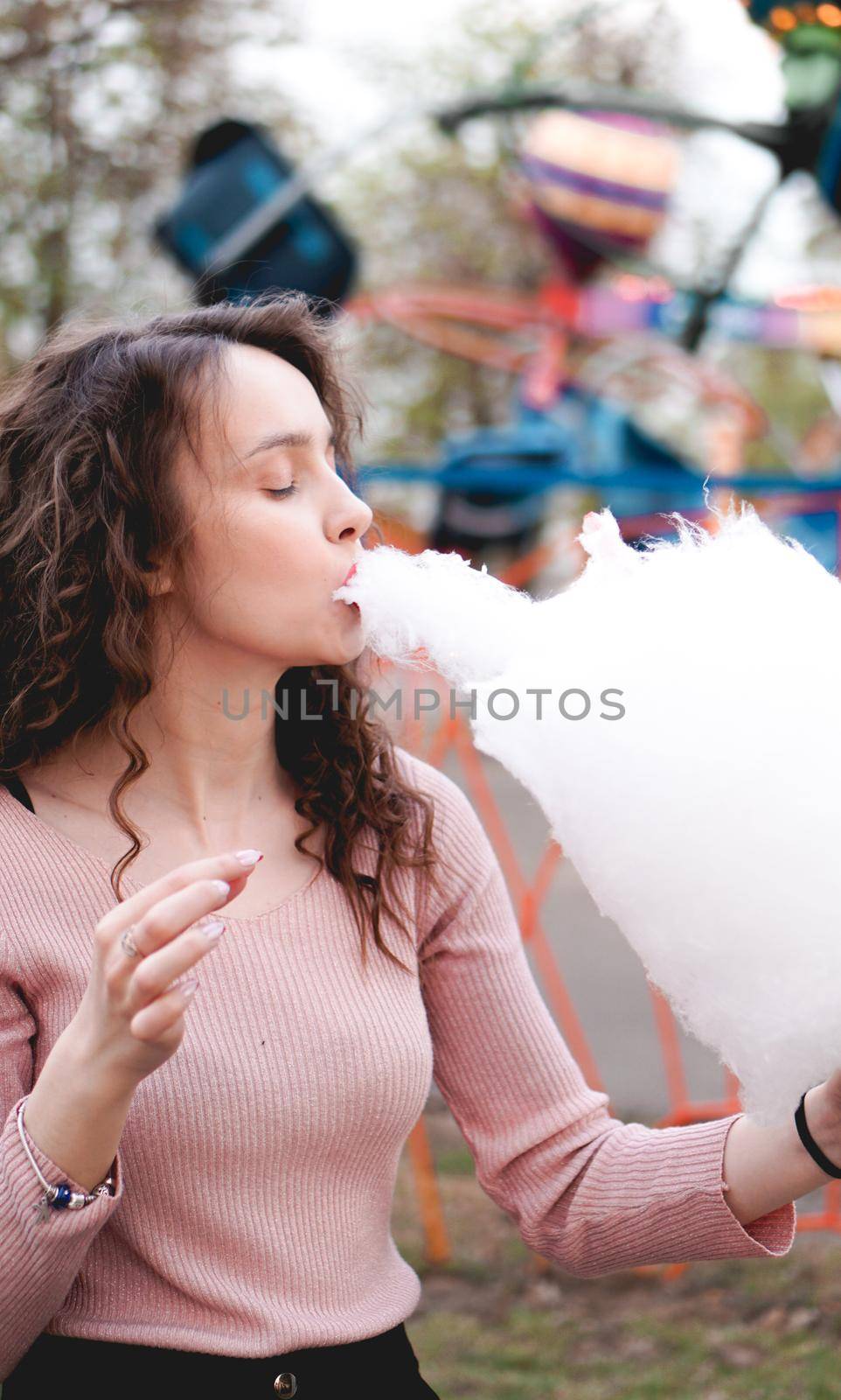 Close up portrait of a happy smiling excited girl holding cotton candy at amusement park