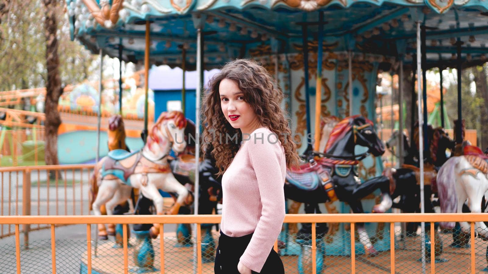 Stylish young hipster woman posing outdoors on the background of carousels by natali_brill