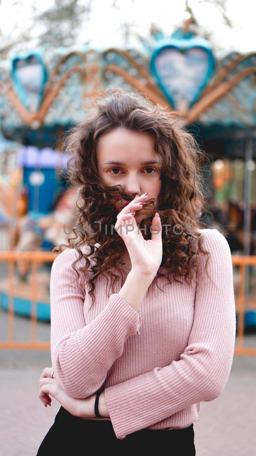 Stylish young hipster woman posing outdoors on the background of carousels by natali_brill
