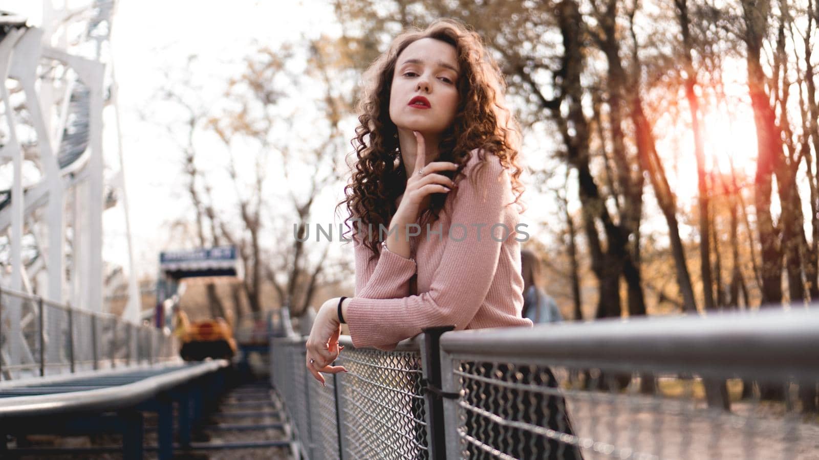 Closeup of a beautiful young woman with curly hair - a sunset behind her