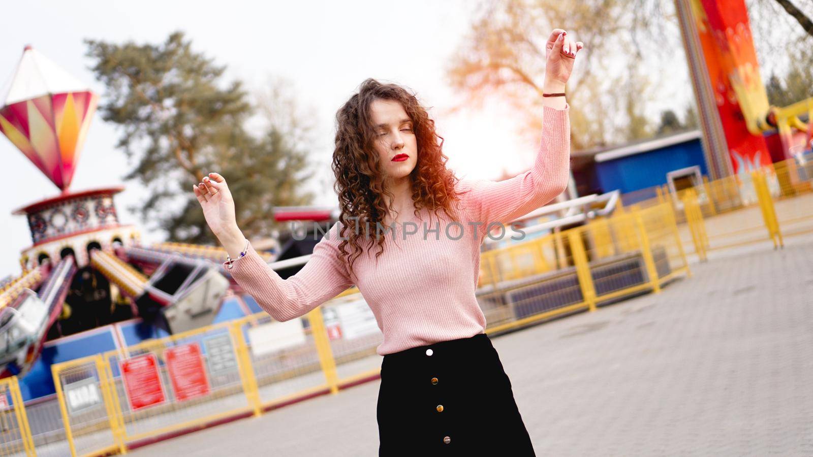Beautiful exited smiling woman having fun and dancing at amusement park at hot summer