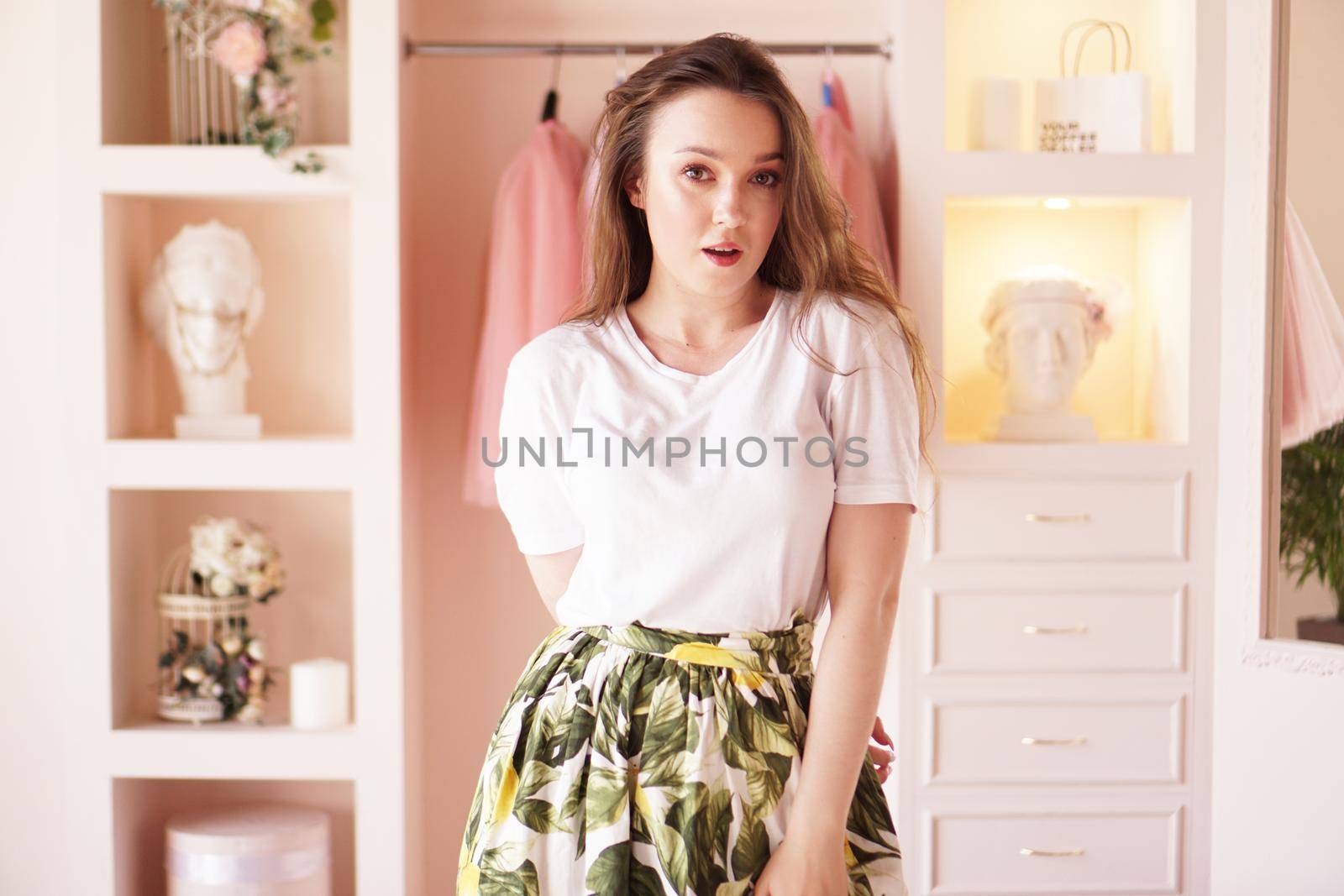 Happy young woman dressing up. Dressing room in pink colors. The concept of fashion and happiness