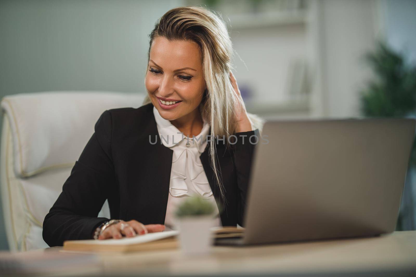 A confident attractive business woman sitting at her office desk and working.