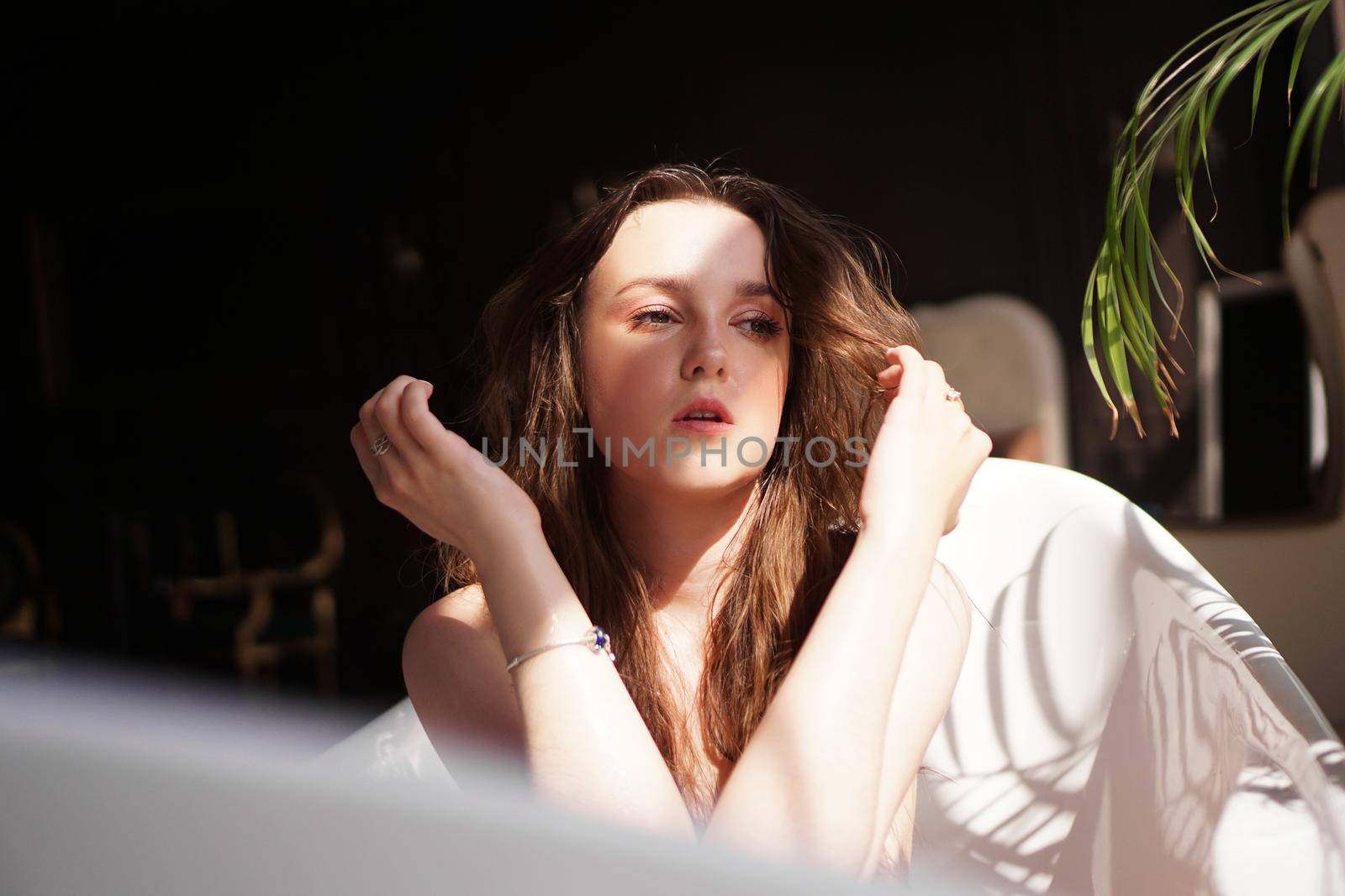 Young attractive woman relaxing in bath - plant in bathroom - sunny day
