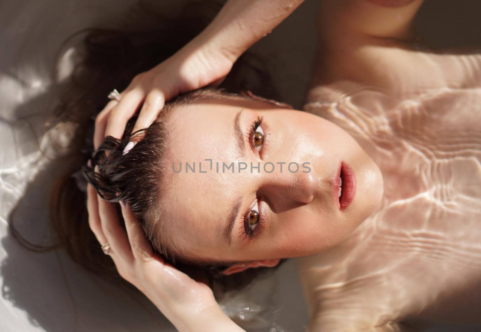 Top view of gorgeous young woman taking a bath and looking at camera