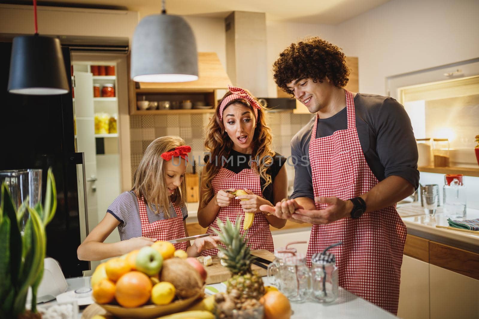 A cheerful parents spending quality time in kitchen at home with theirs cute daughter.