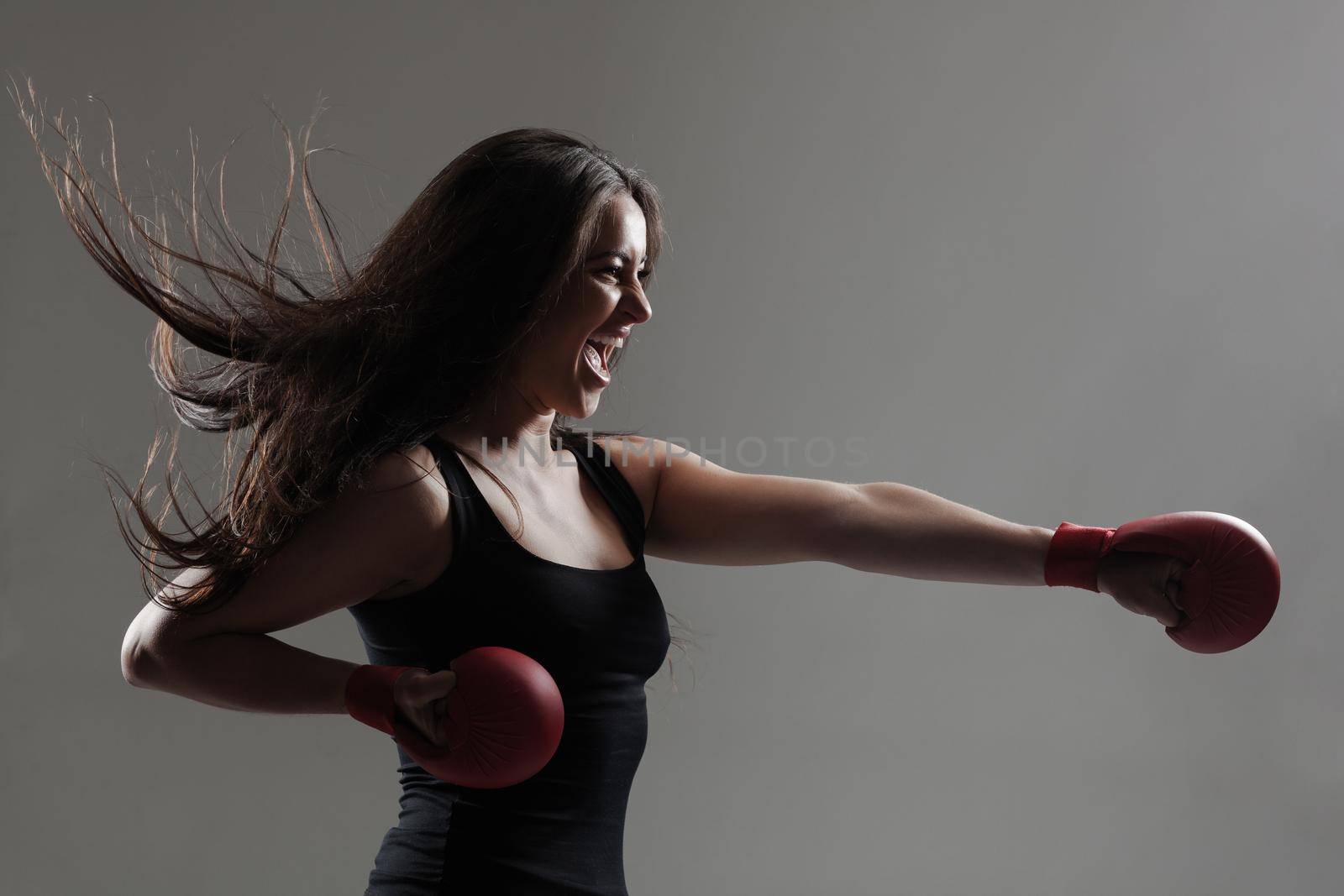 girl exercising karate punch and screaming against gray background by kokimk