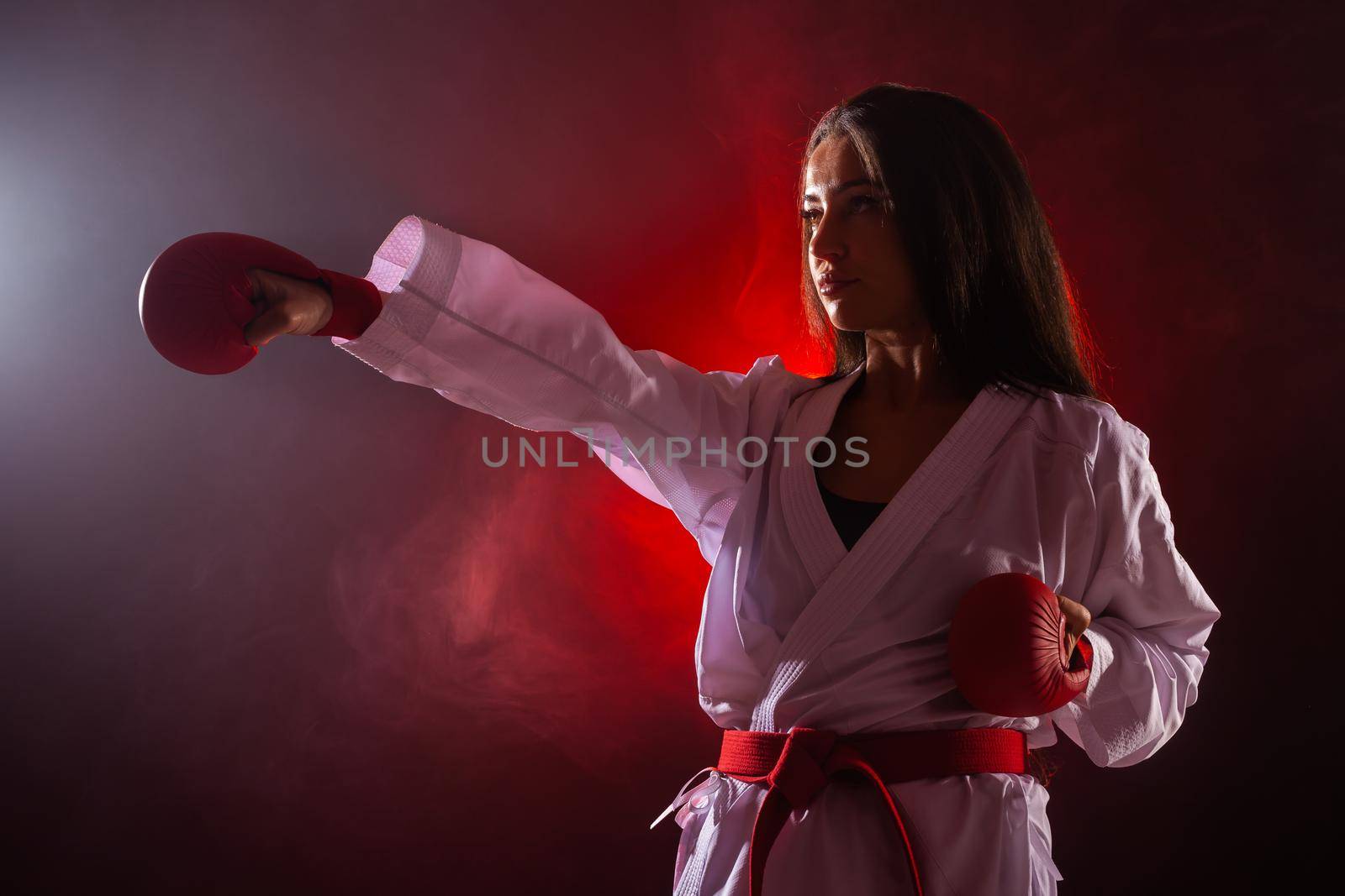 girl exercising karate punch against red fog background. by kokimk
