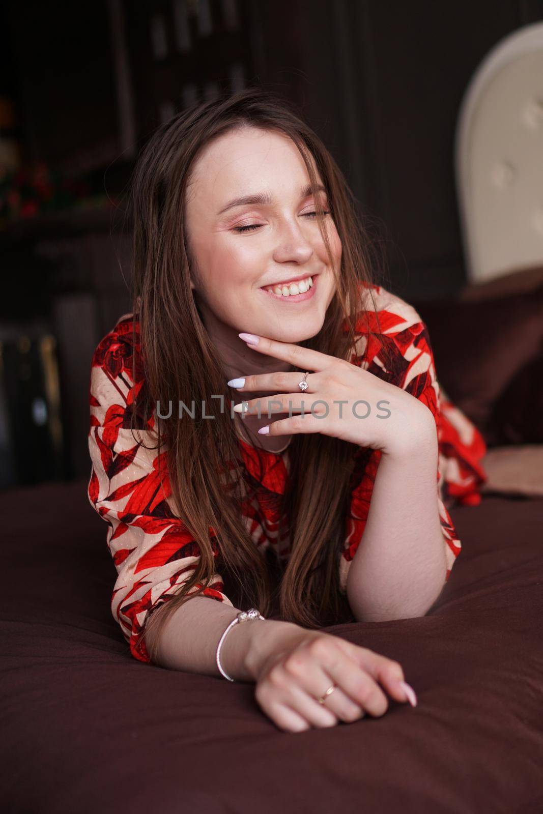 Happy young woman. Relaxed woman lying on a brown bed by natali_brill