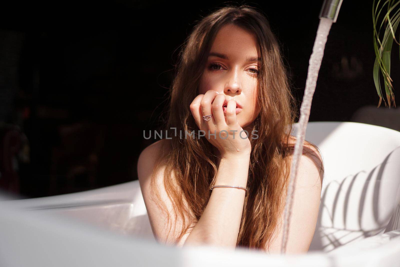 An Attractive girl relaxing in bath on dark background - fashion portrait