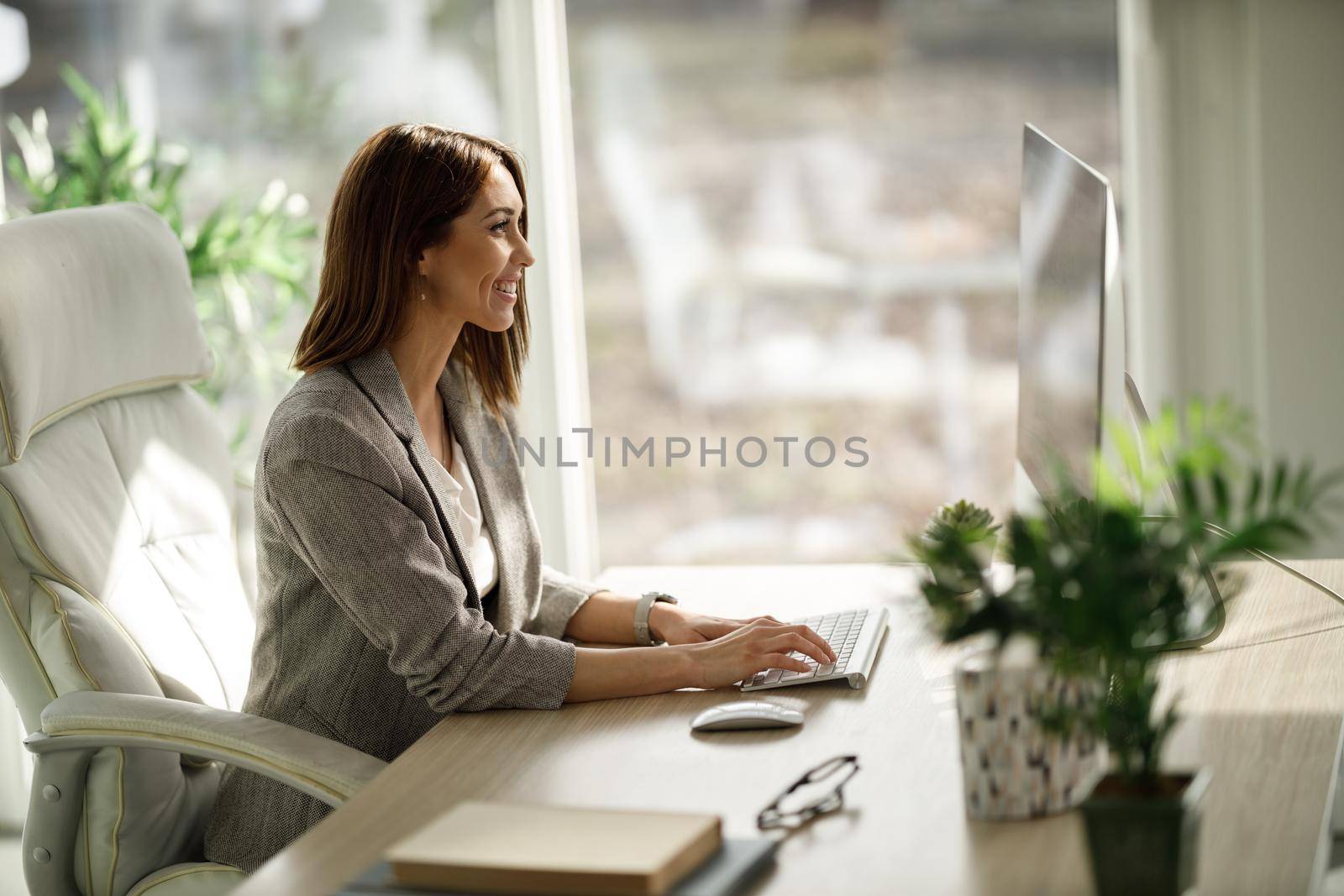 An attractive business woman sitting alone in her home office and working on computer.