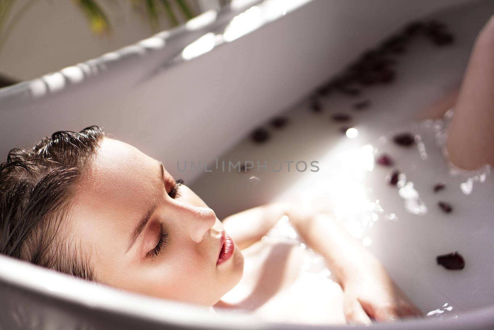 An Attractive girl relaxing in bath on light background by natali_brill