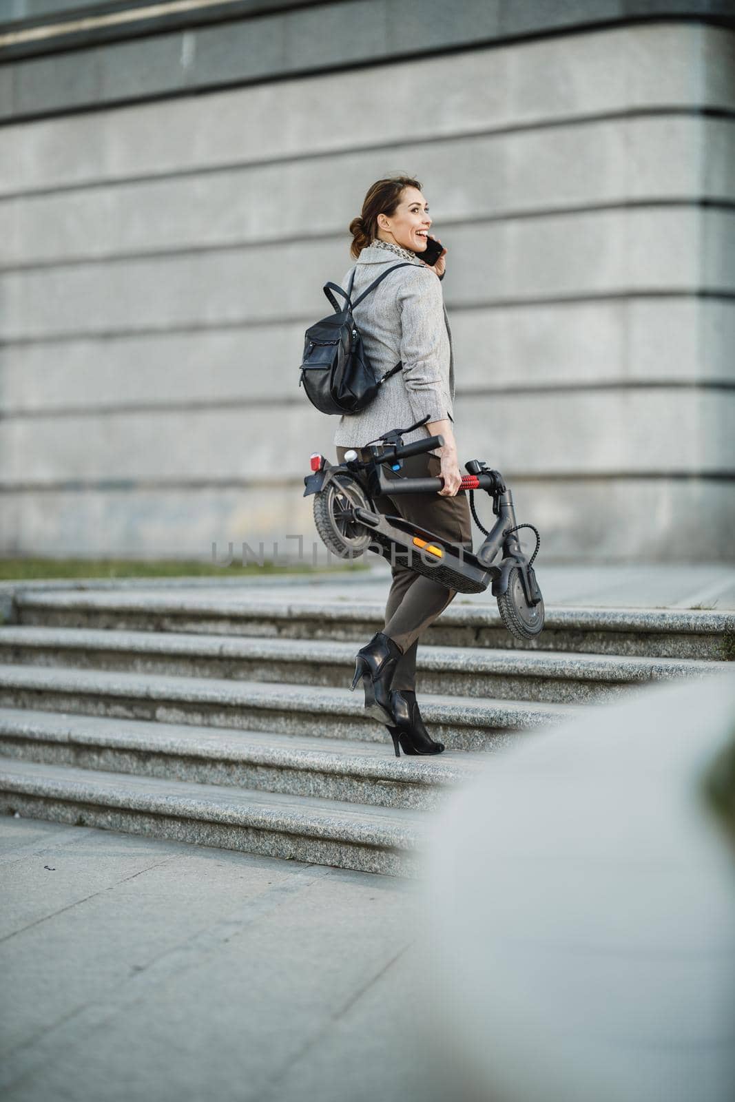 A young businesswoman with an electric push scooter going to work.