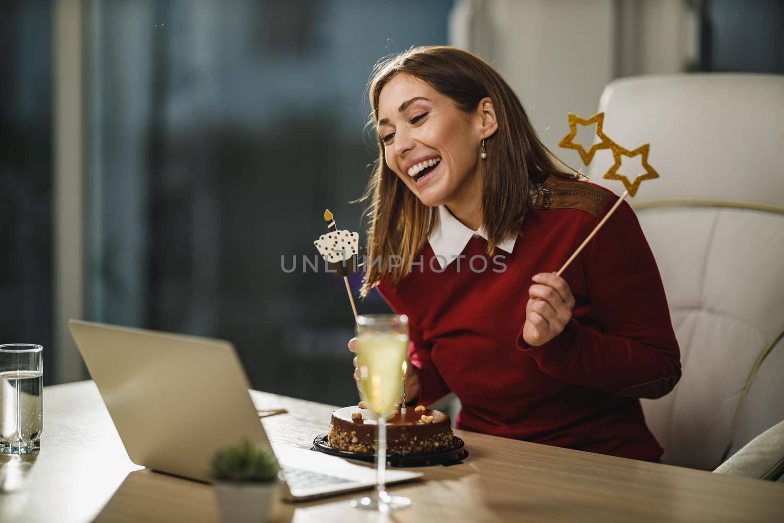 Cheerful young woman have video conference with friends while birthday celebration at home during pandemic isolation.