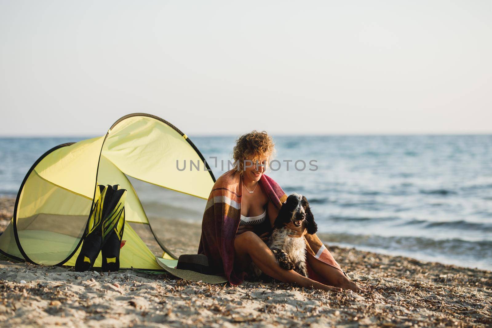 Young woman spending day at the beach with her cute Cocker Spaniel dog. 