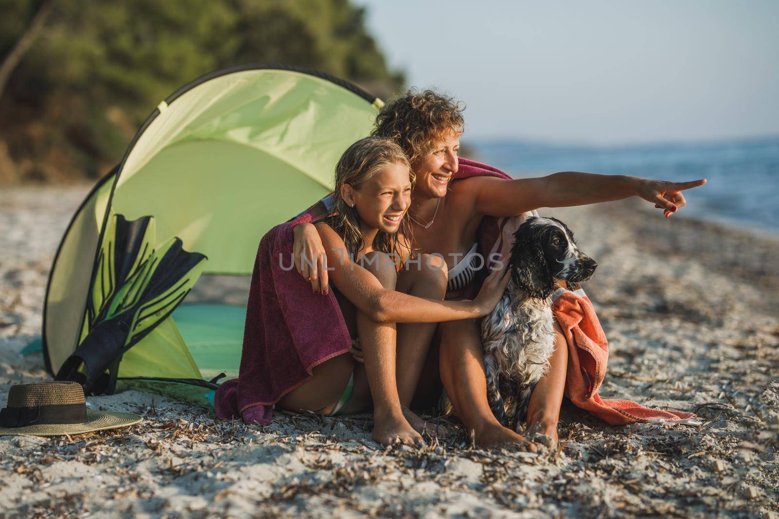 Young mom and her teen daughter spending day at the beach with their cute Cocker Spaniel dog. 