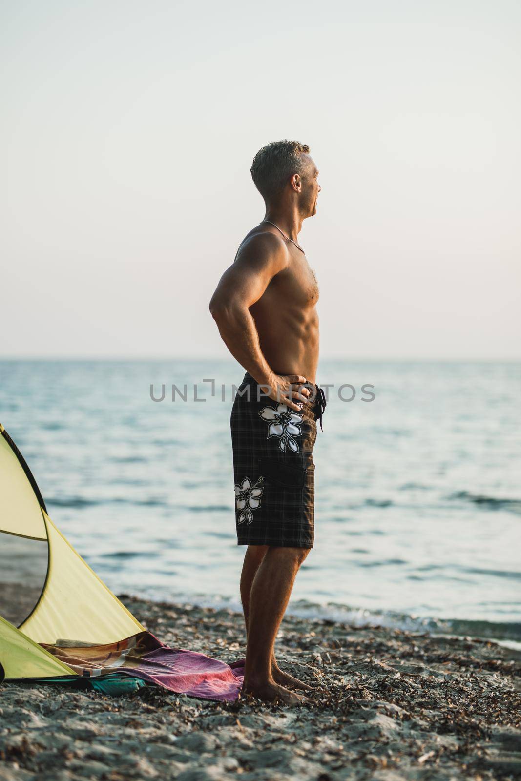 A handsome man enjoying and watching the sun go down at the beach.