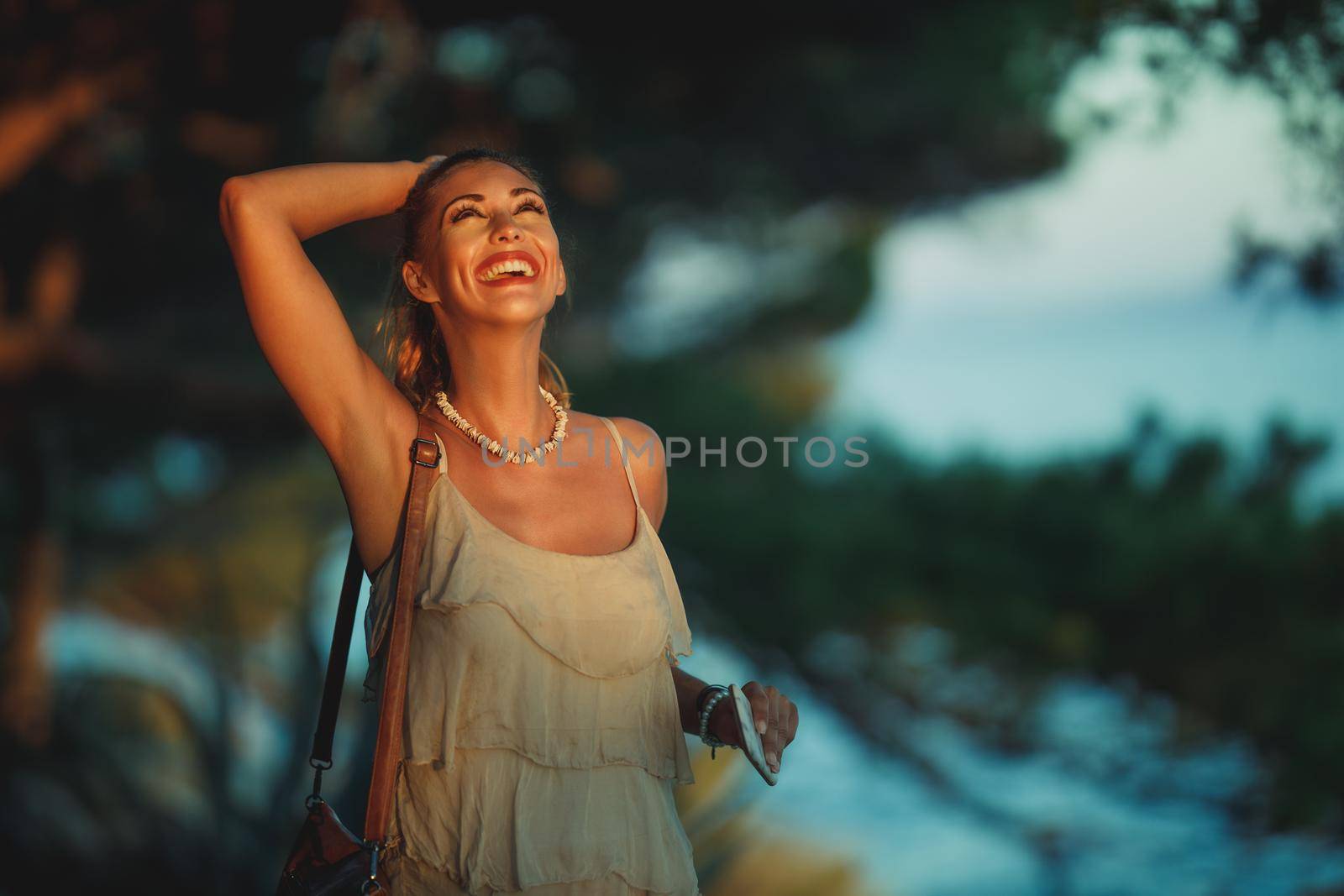 A cheerful young woman enjoying a summer vacation while walking through pine forest near Mediterranean sea.
