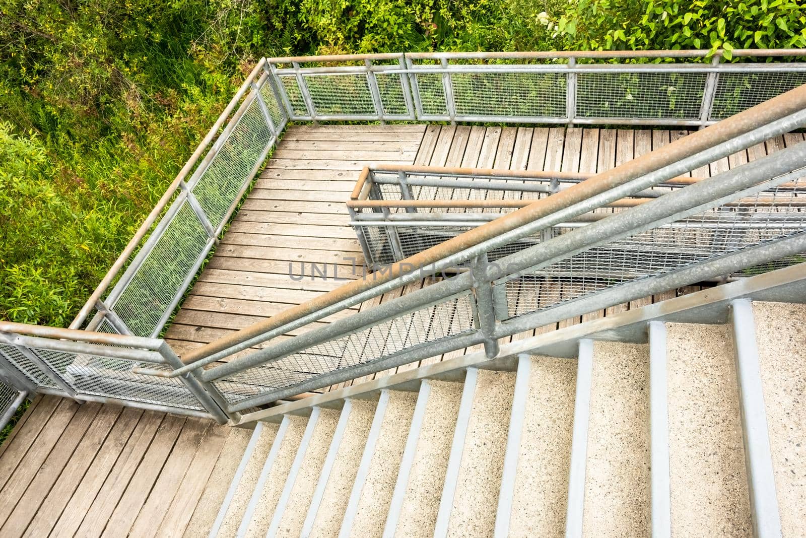 Stair and wooden deck with metal rails in a park.