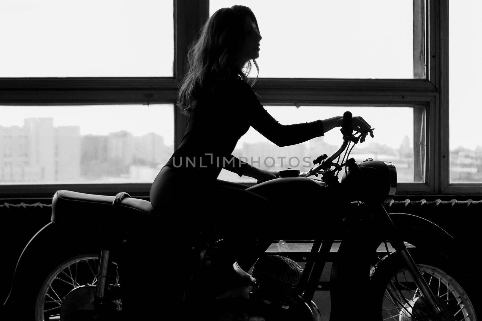 A silhouette of a woman sitting on a motorcycle by natali_brill