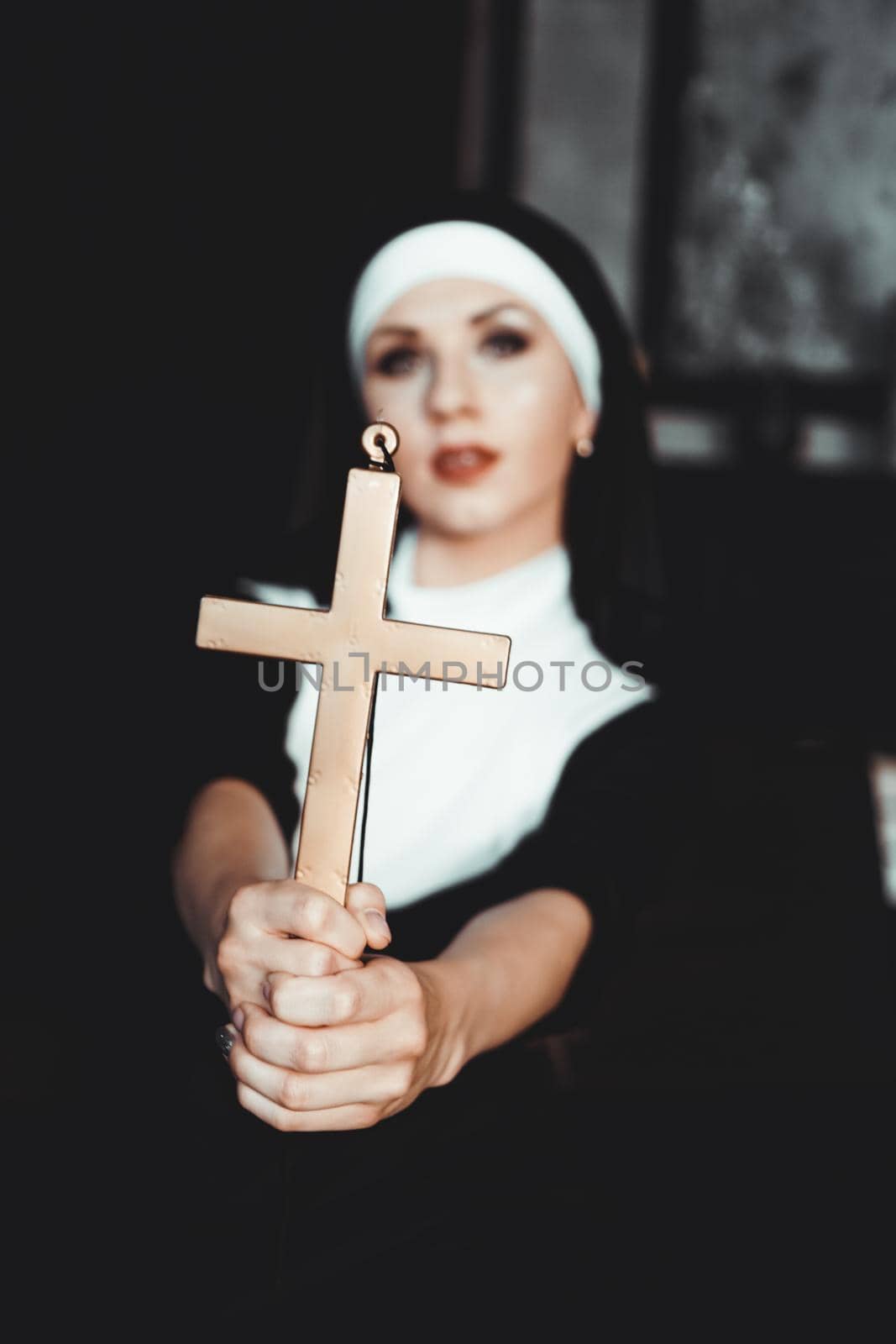 Nun holding a cross. The concept of religion. Young beautiful nun expels the devil