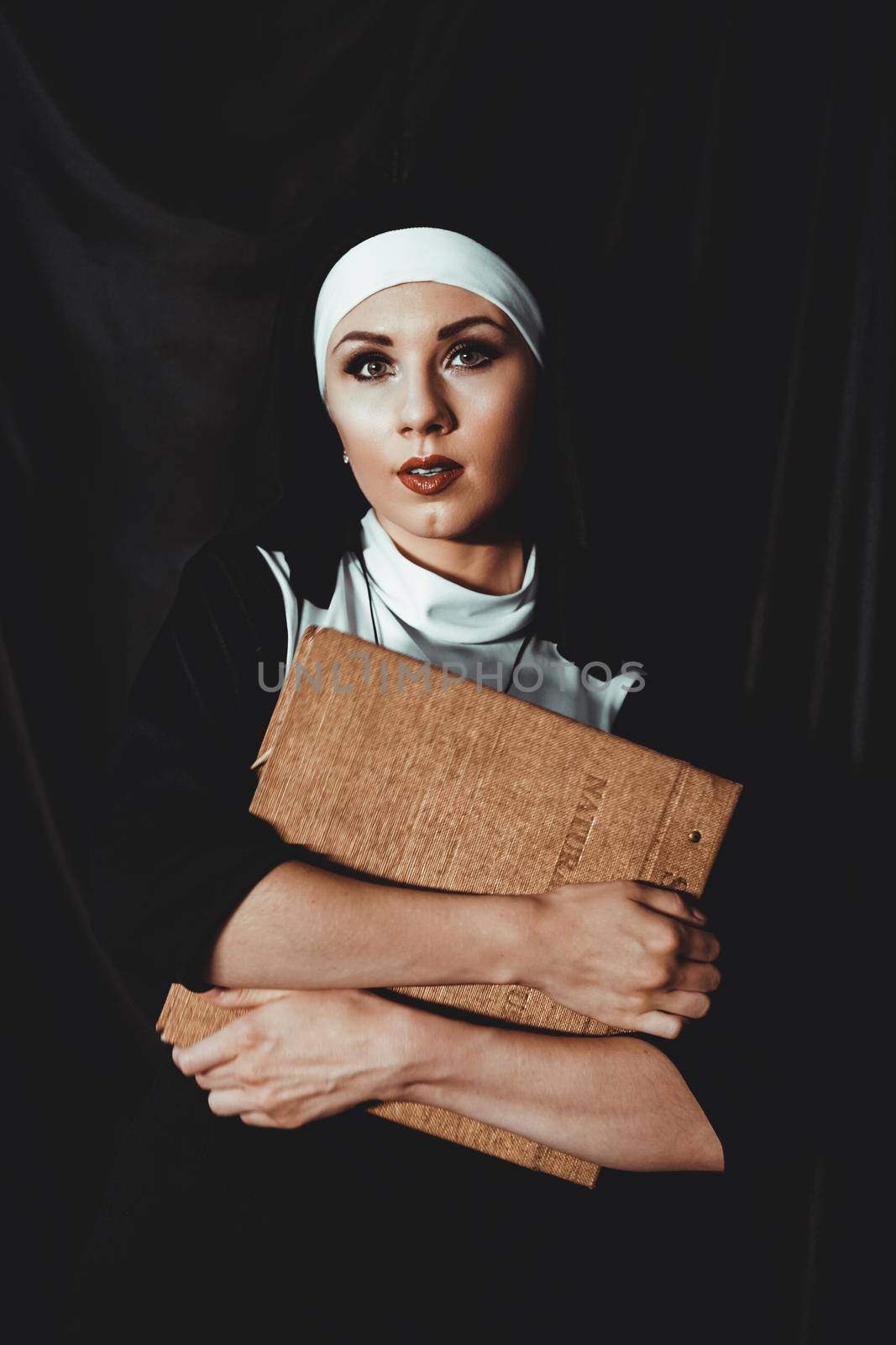 Beautiful young nun in religion black suit holds Bible. Religion concept by natali_brill