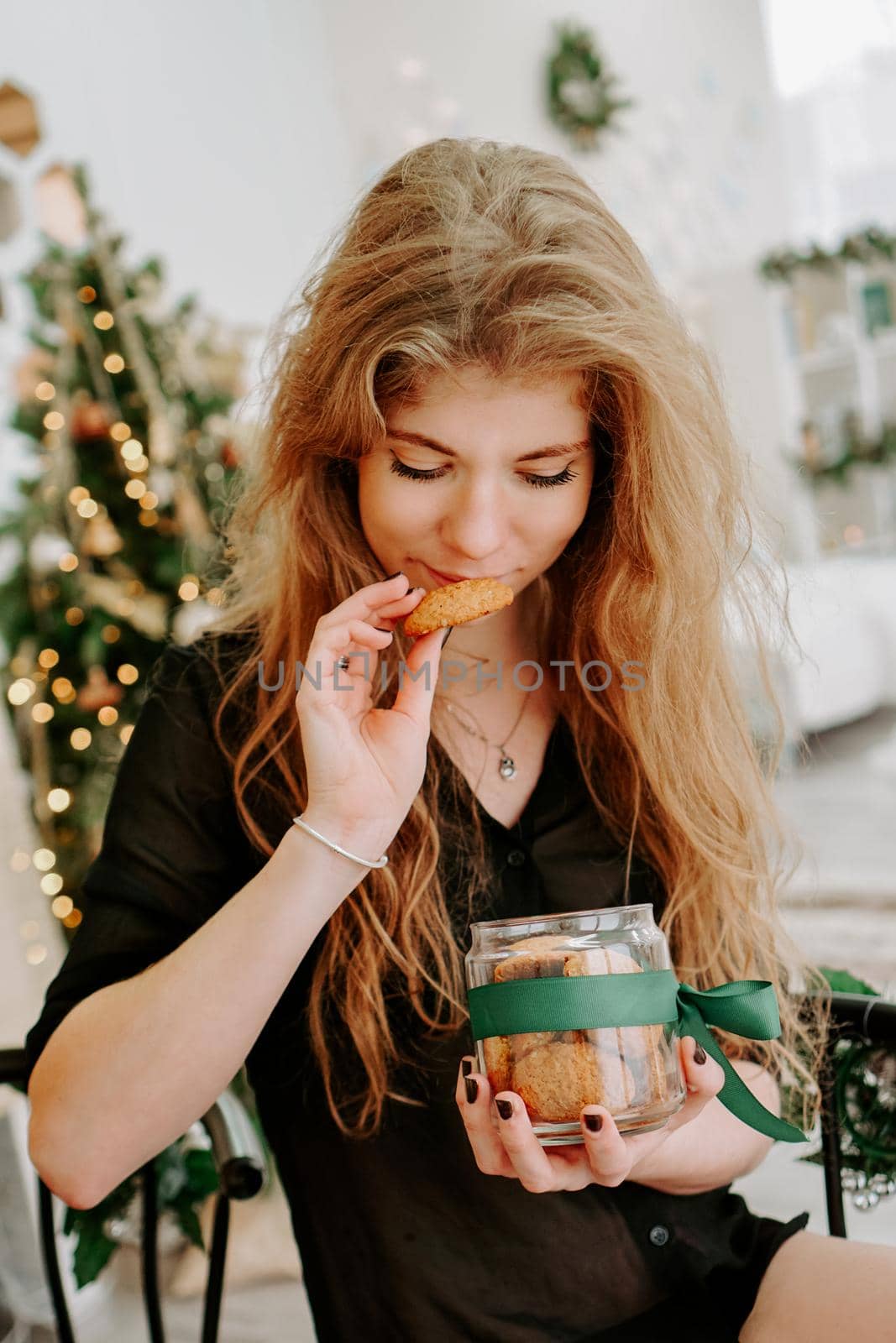 Happy young woman having eating christmas cookies in kitchen by natali_brill