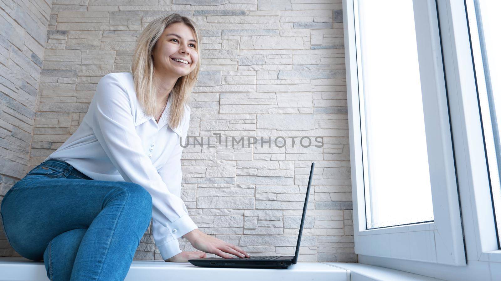 Side view. Young business woman sitting and taking notes in notebook. Student learning online. Blogger with laptop.