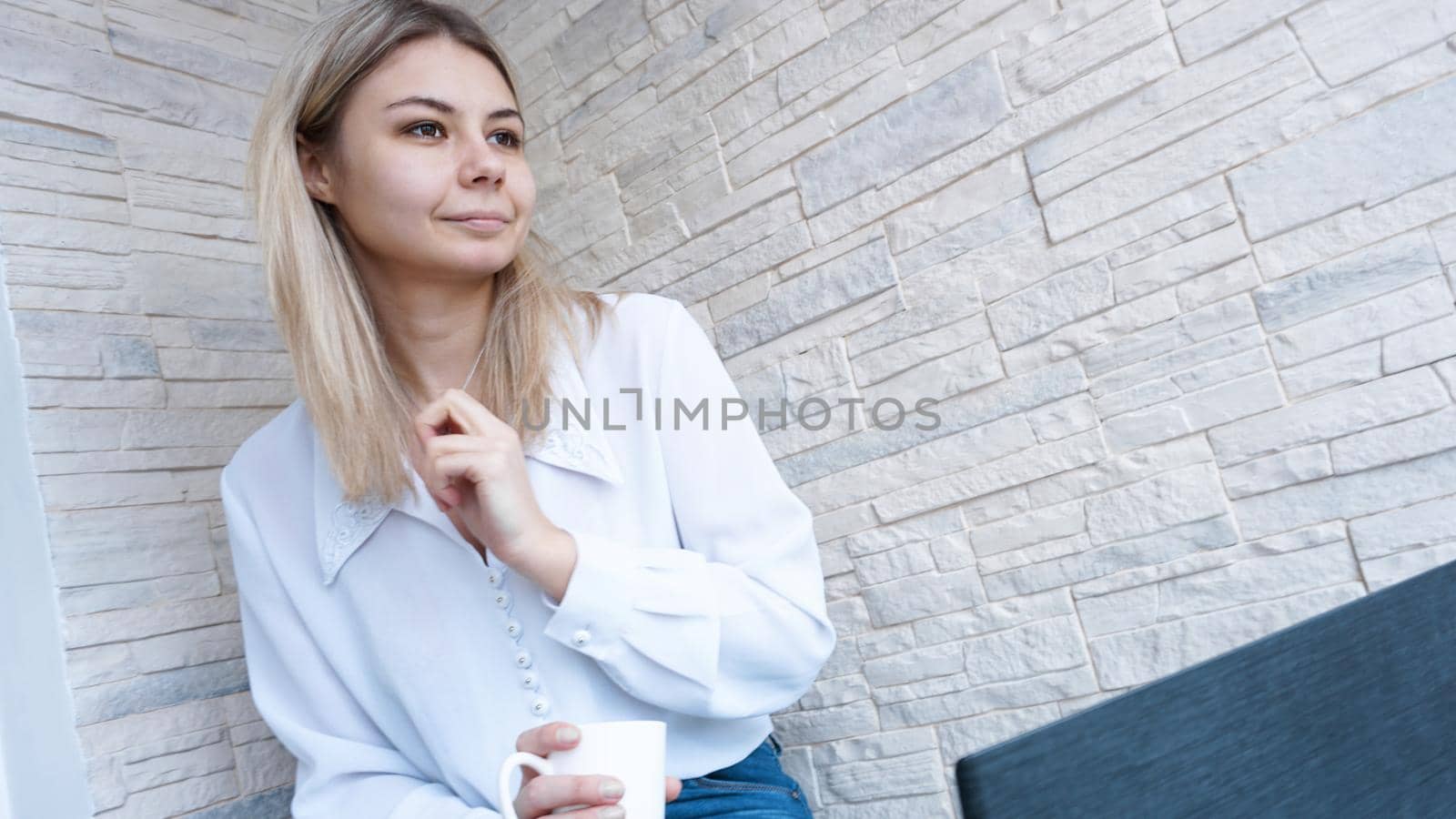 Side view. Young business woman with a cup of coffee sitting and taking notes in notebook. Student learning online. Blogger with laptop.