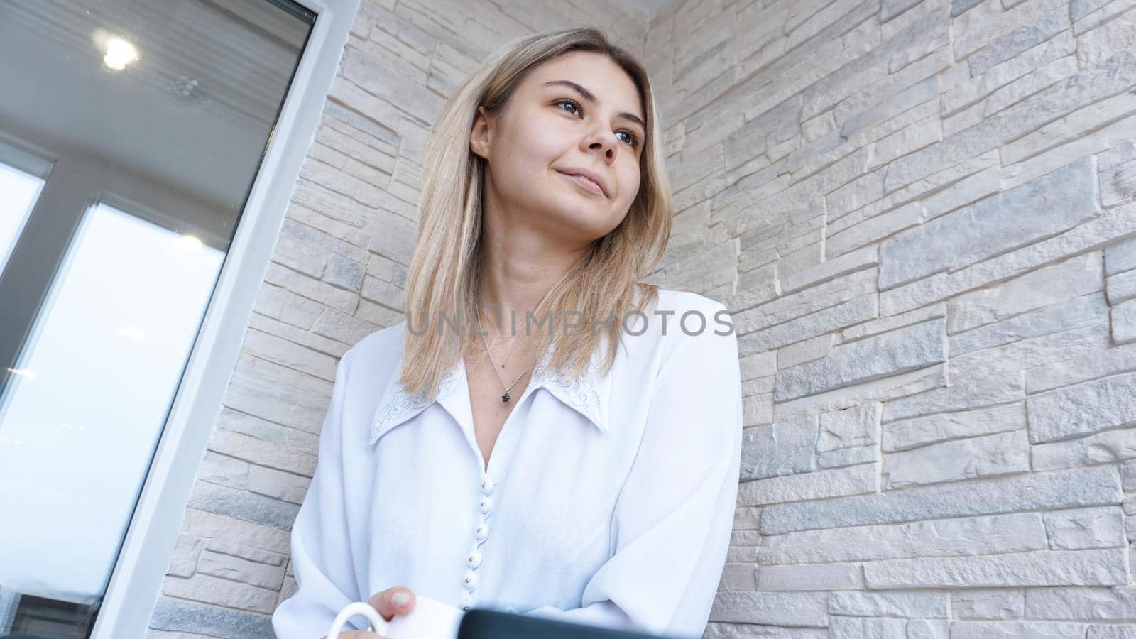 Side view. Young business woman with a cup of coffee sitting and taking notes in notebook. Student learning online. Blogger with laptop.