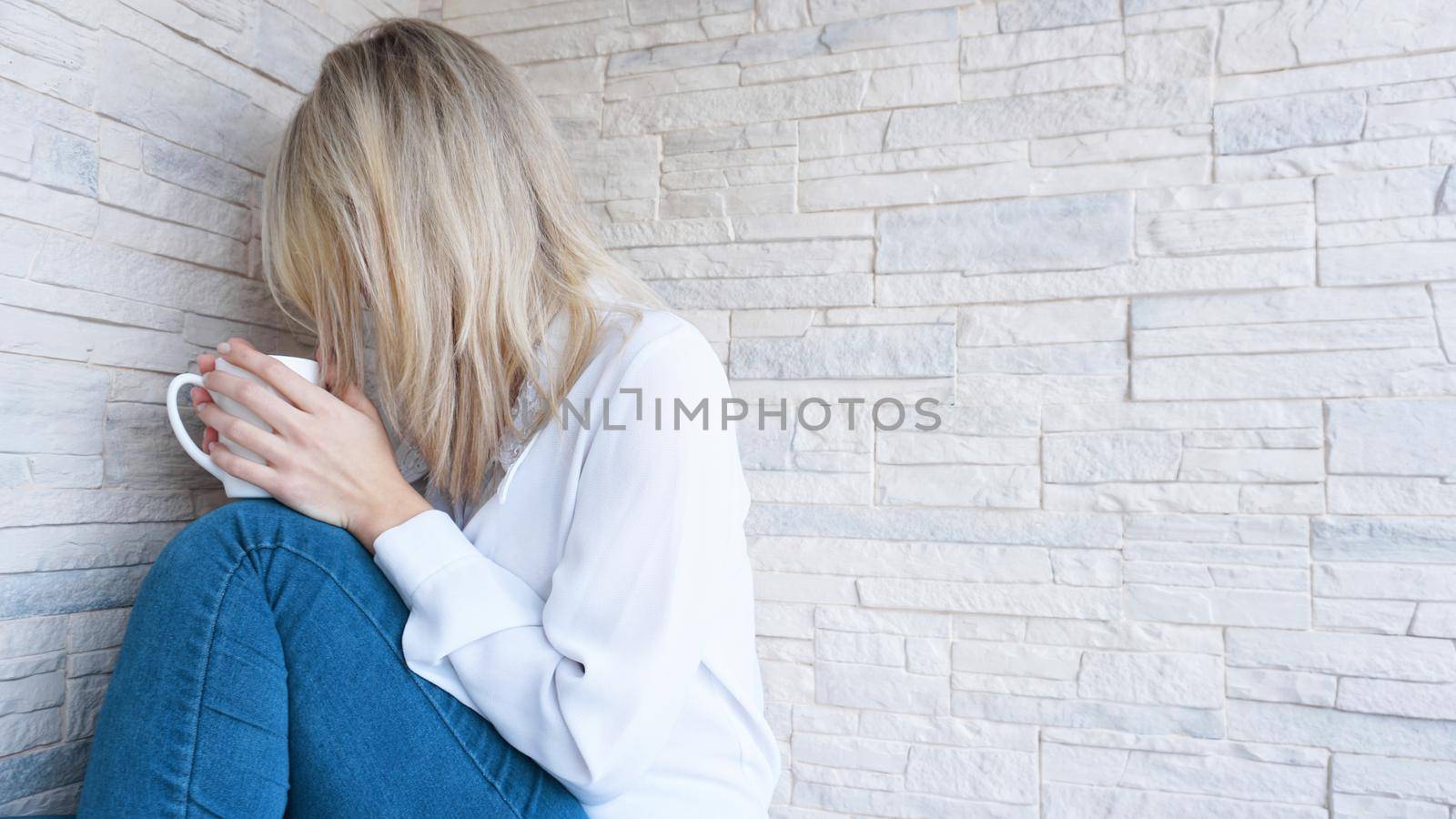 Sad or Depressed Young Beautiful Woman at home on brick wall background