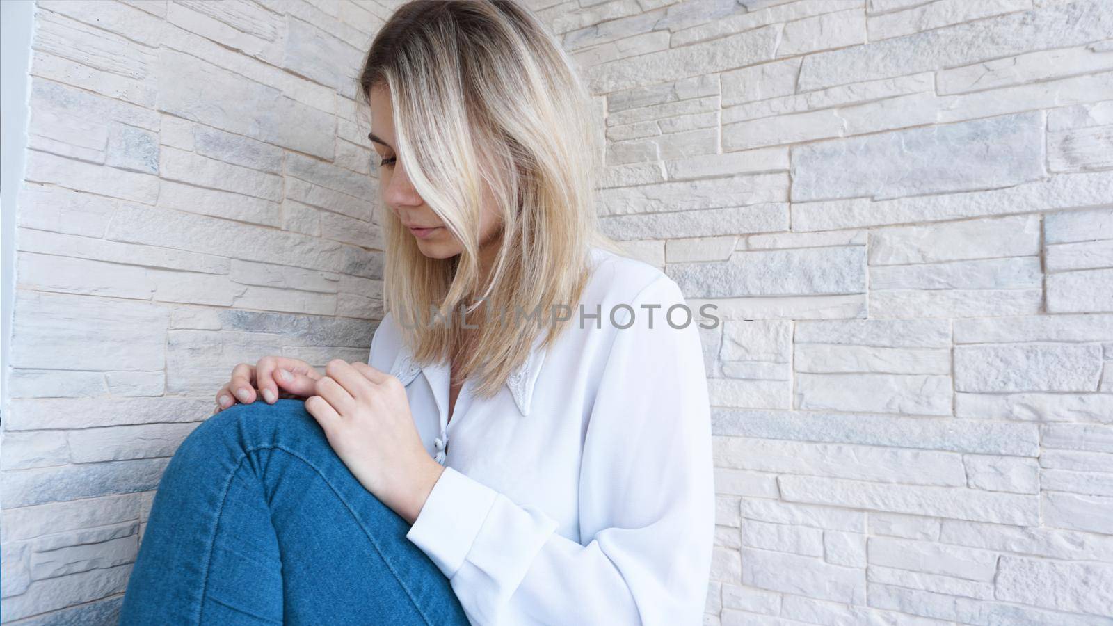 Sad or Depressed Young Beautiful Woman at home on brick wall background