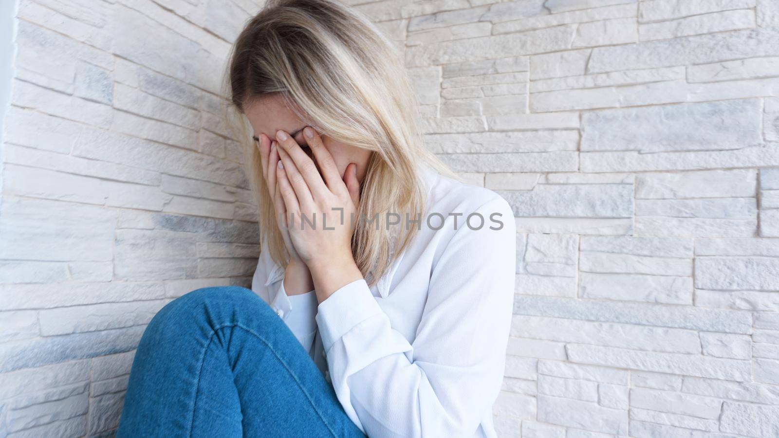 Sad or Depressed Young Beautiful Woman at home on brick wall background