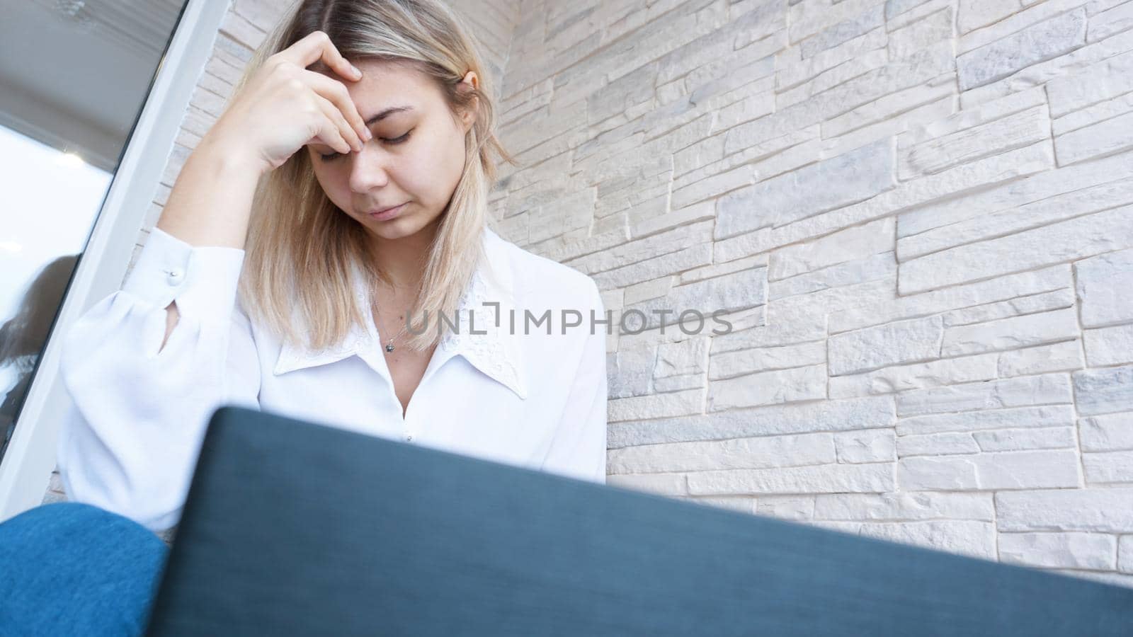 Woman looks at her laptop with a pained worried expression. Female employee is stressed out of work, touching aching head, reading email, solving a problem.