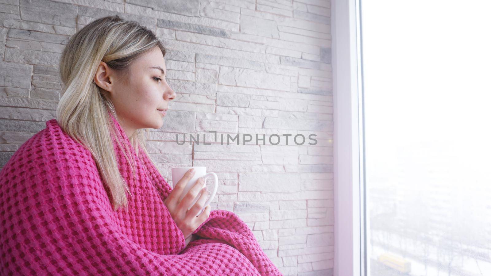 Beautiful young girl in a pink plaid with a cup of coffee. Young woman on balcony. Rest for a cup of coffee for cozy breakfast.