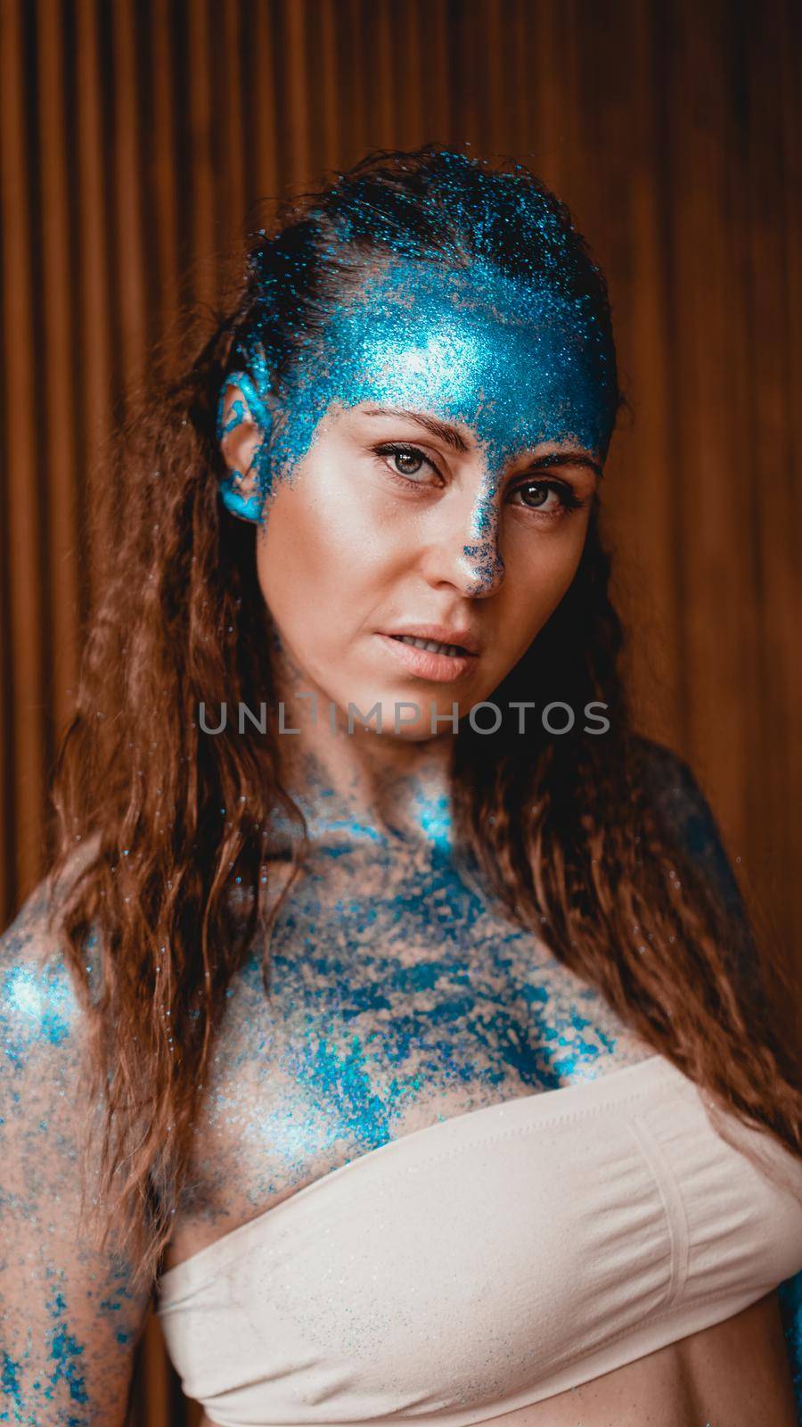 Portrait of beautiful woman with blue sparkles on her face in the bath. The concept of Individuality