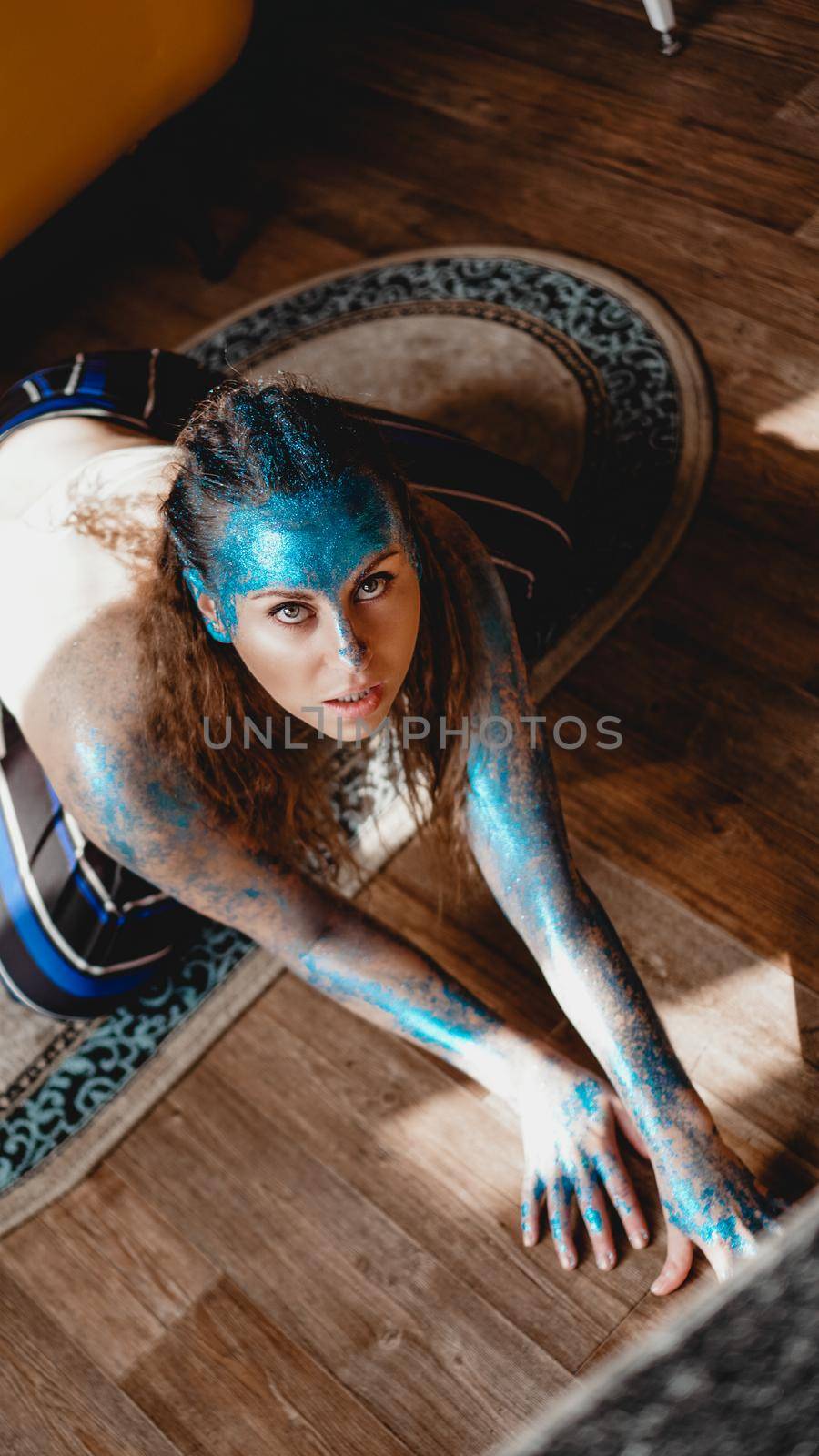 Portrait of beautiful woman with blue sparkles on her face. The concept of freaks and aliens. People are different from others. Individuality