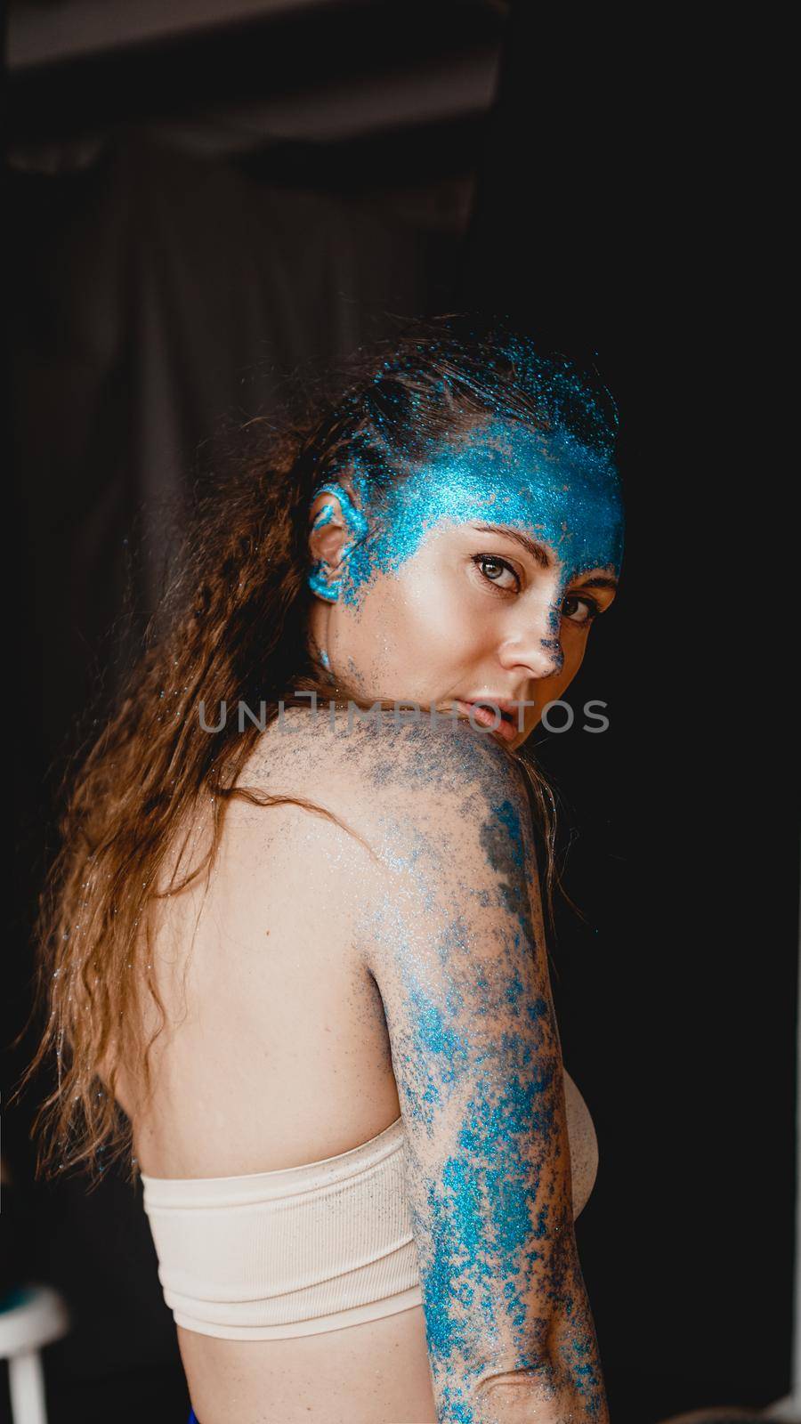 Portrait of beautiful woman with blue sparkles on her face. The concept of freaks and aliens. People are different from others. Individuality