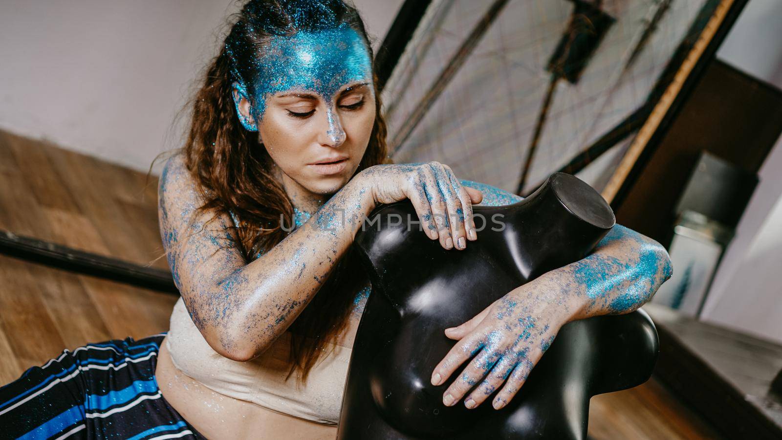 Artist in workshop. Woman with blue sparkles on her face. The concept of freaks and creative people. People are different from others. Individuality