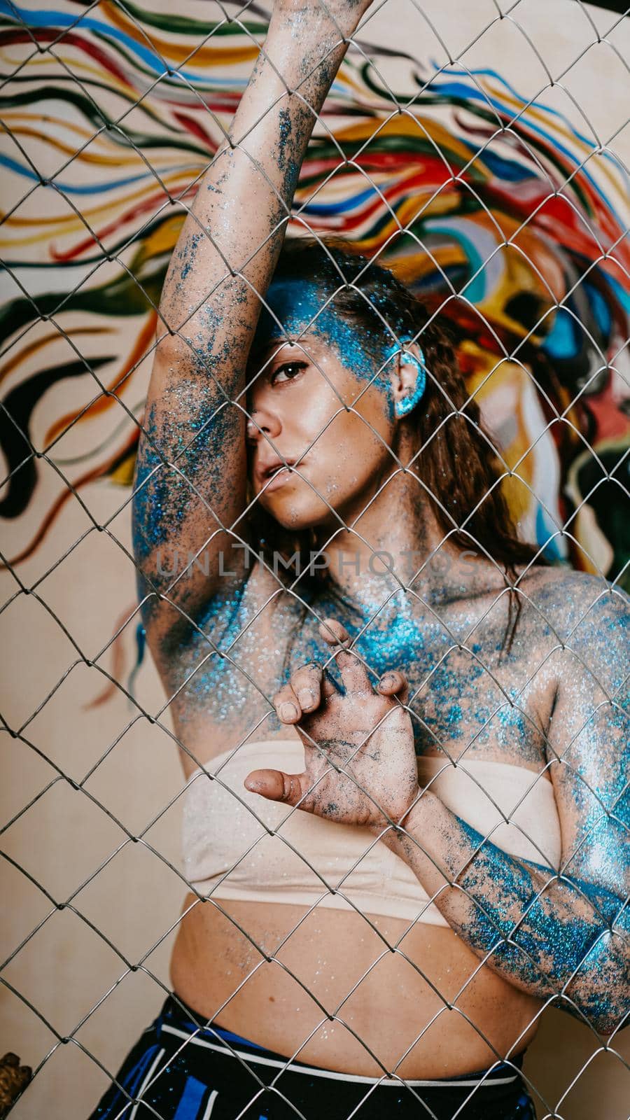 Brunette girl behind the net. Portrait of beautiful woman with blue sparkles on her face. The concept of people with Individuality